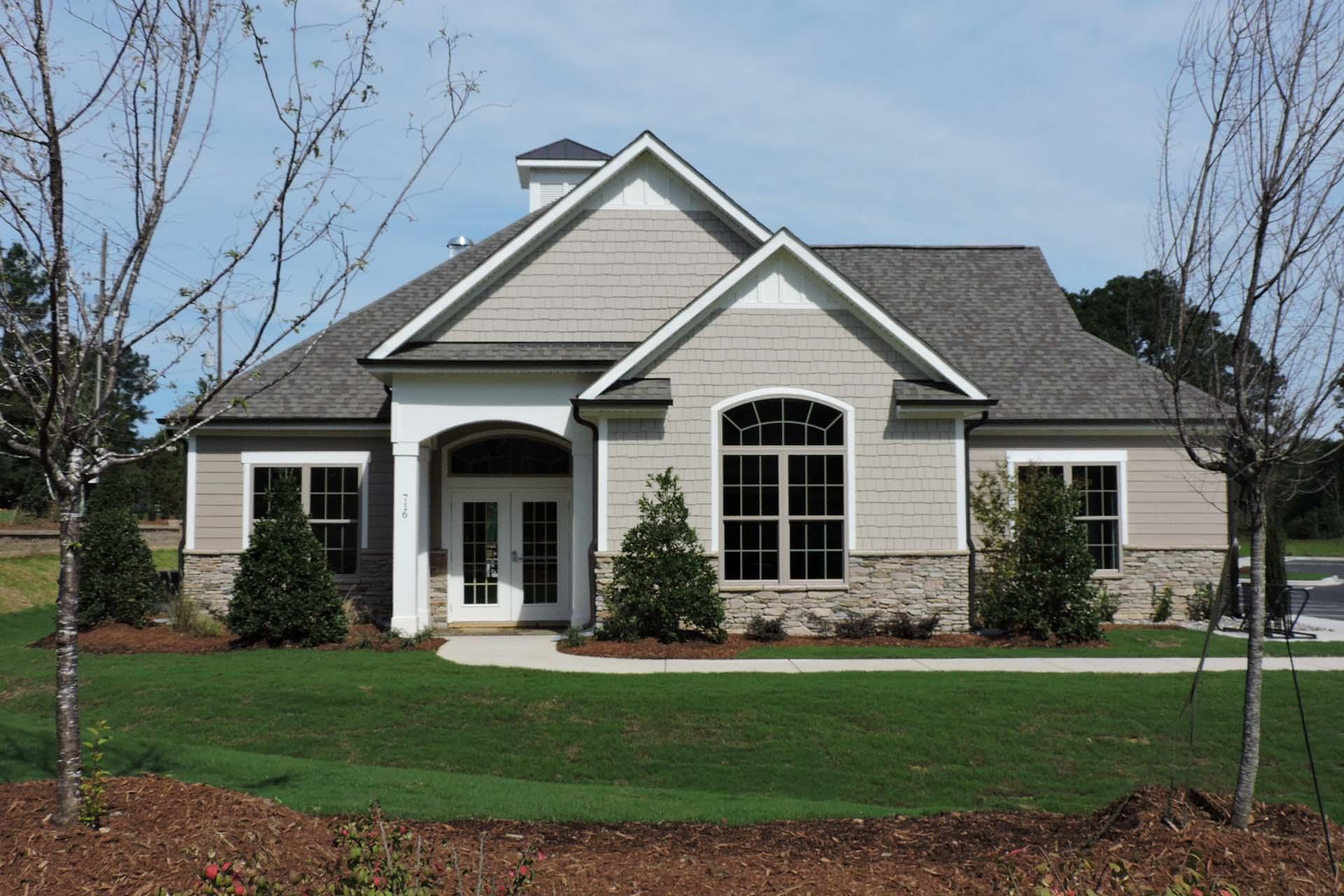 Modern clubhouse exterior at Glenmere in Knightdale NC with gabled roof arched windows covered porch and landscaped poolside grounds