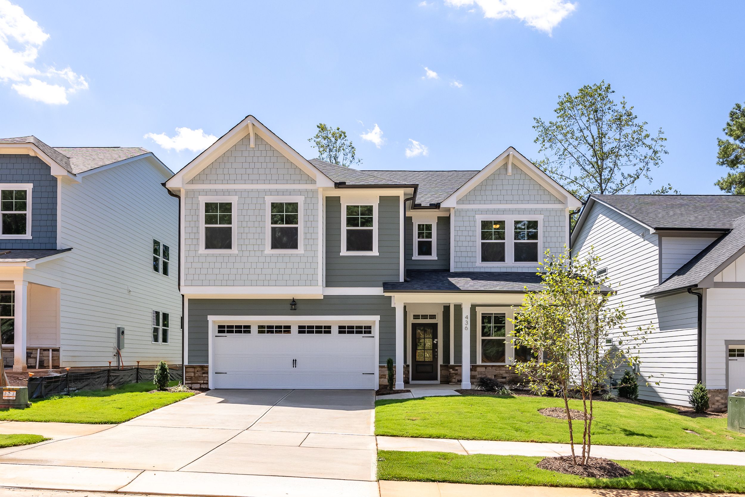 Two-story Aspen C home with stone and vinyl exterior, two-car garage, and landscaped yard in Holly Springs, NC