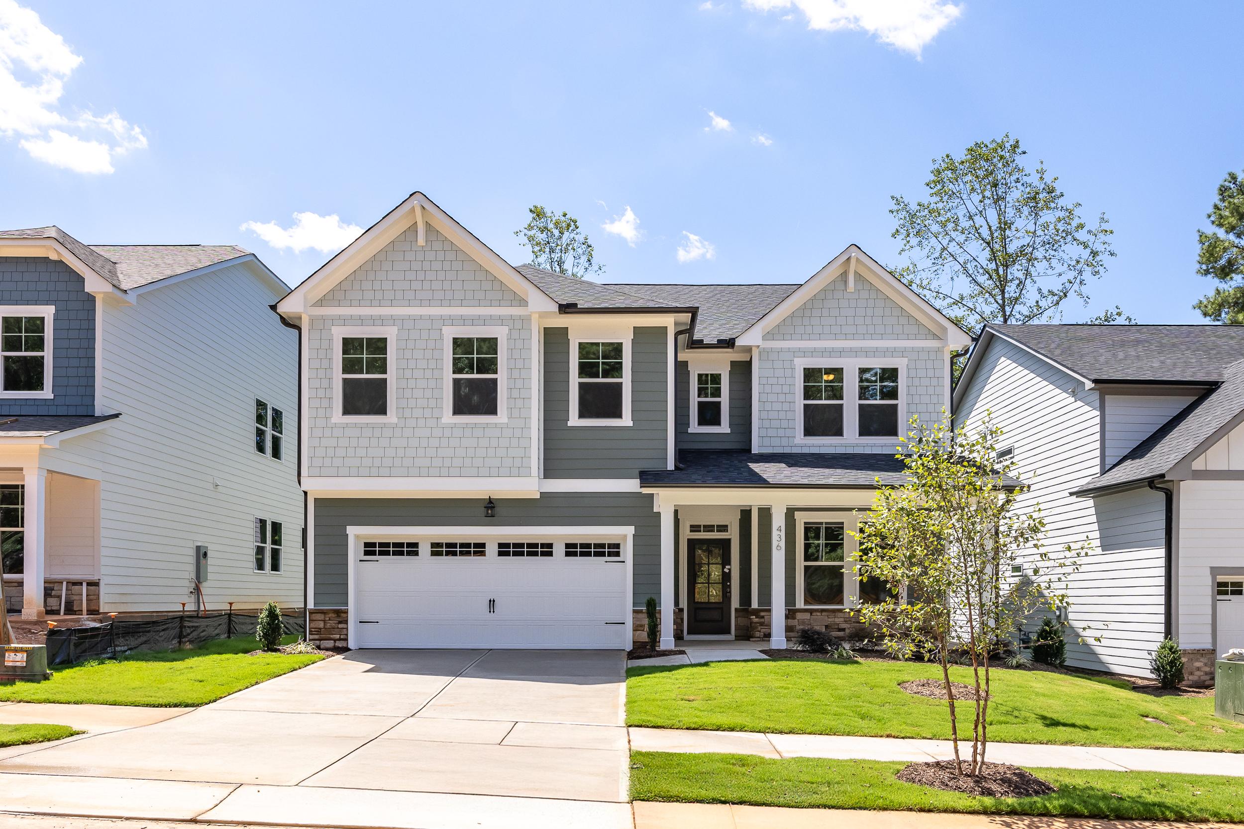 Two-story Aspen C home with stone and vinyl exterior, two-car garage, and landscaped yard in Holly Springs, NC
