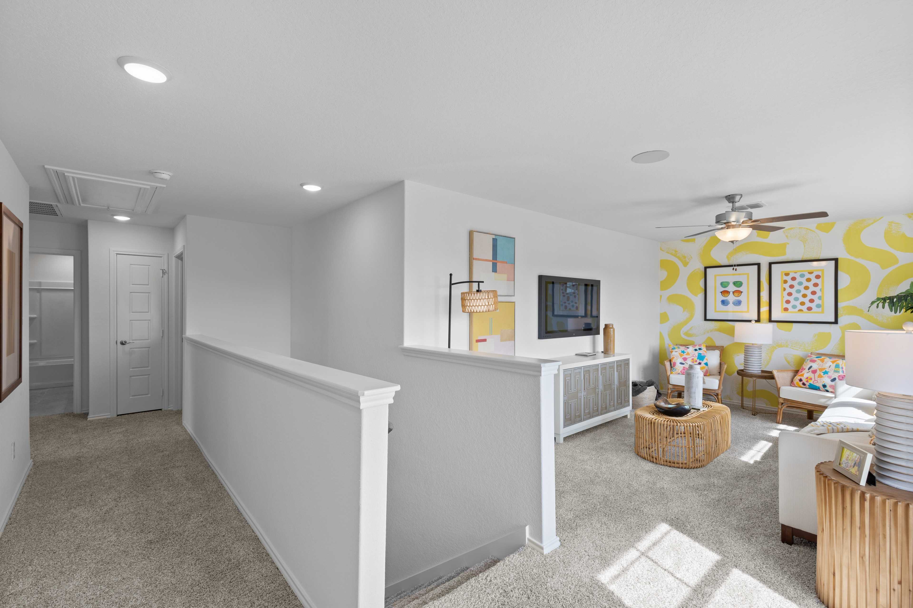 Spacious upstairs loft at Horizon Pointe in Converse Texas with white sofa, colorful abstract art, rattan tables and ceiling fan