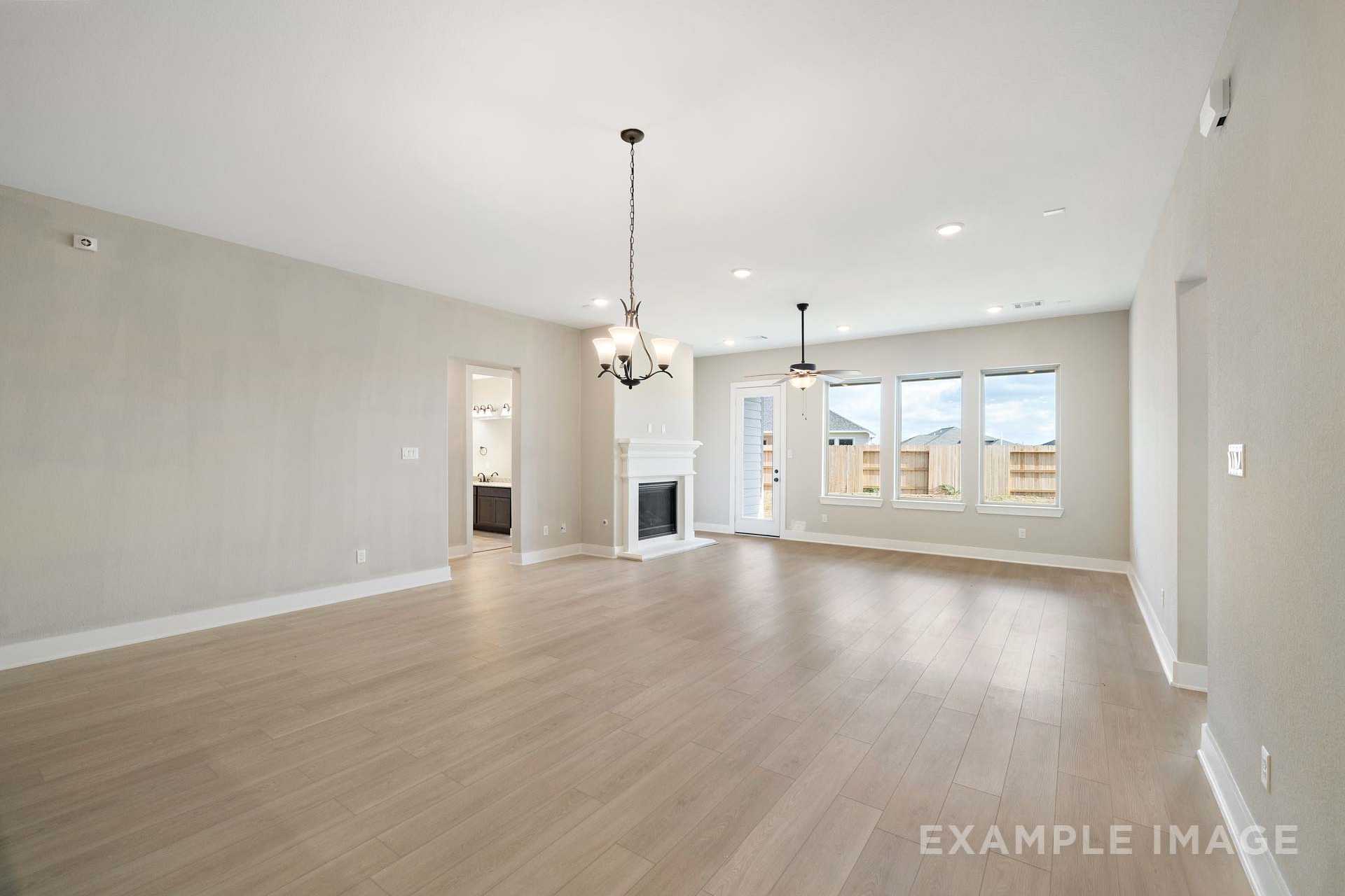 Spacious open-concept living room in The Elizabeth A with fireplace, hardwood floors, large windows, and neutral walls