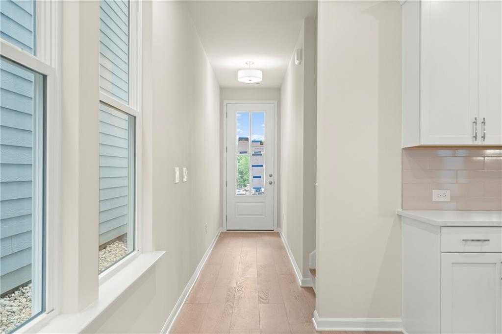 Bright hallway with oak hardwood floors, large side windows, glass-back door, and adjacent white kitchen in Davidson Homes The Cary A, Kennesaw GA