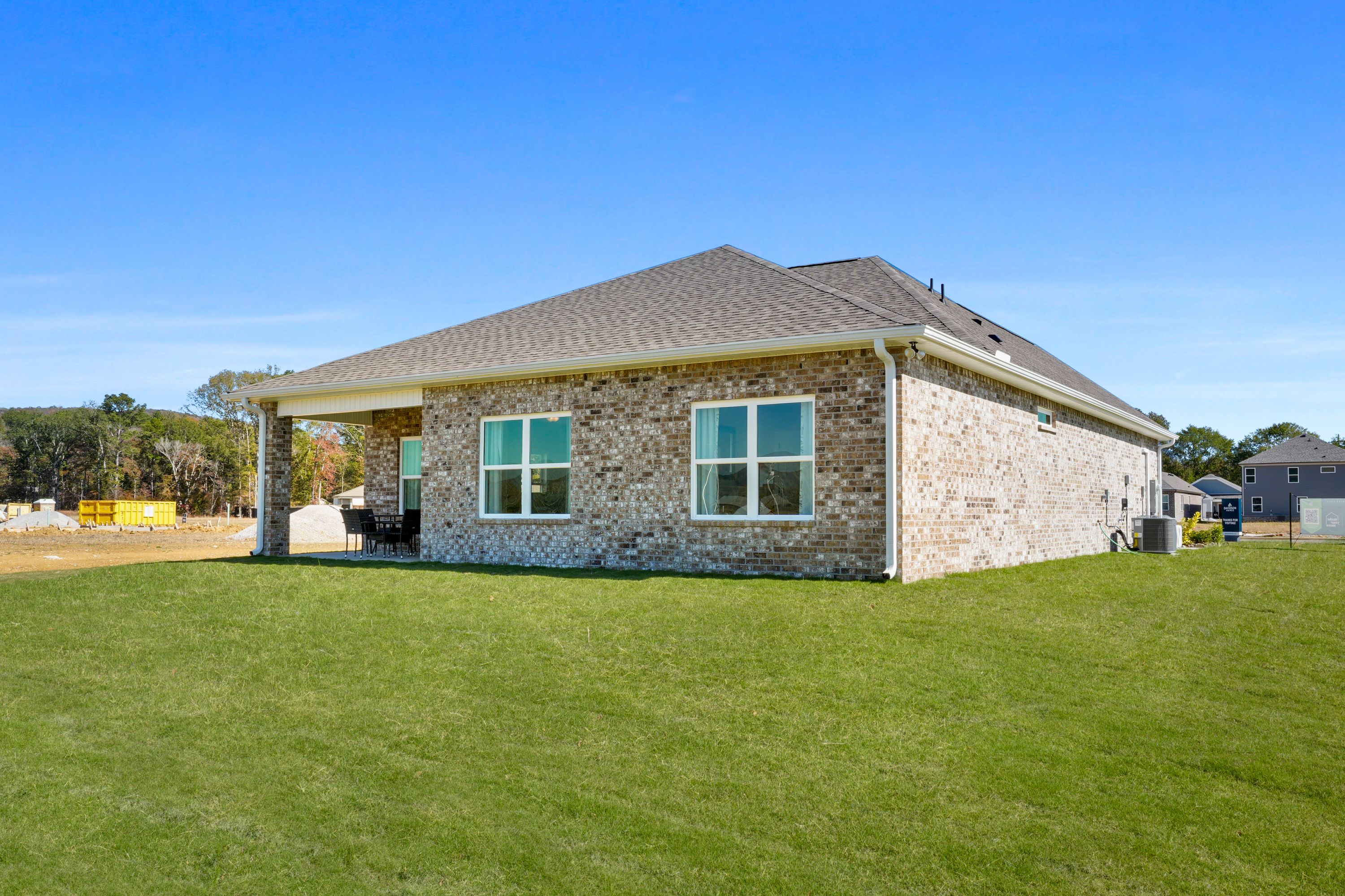 Brick home side exterior at Ramsay Cove in Owens Cross Roads, Alabama with covered patio, large windows, and green lawn
