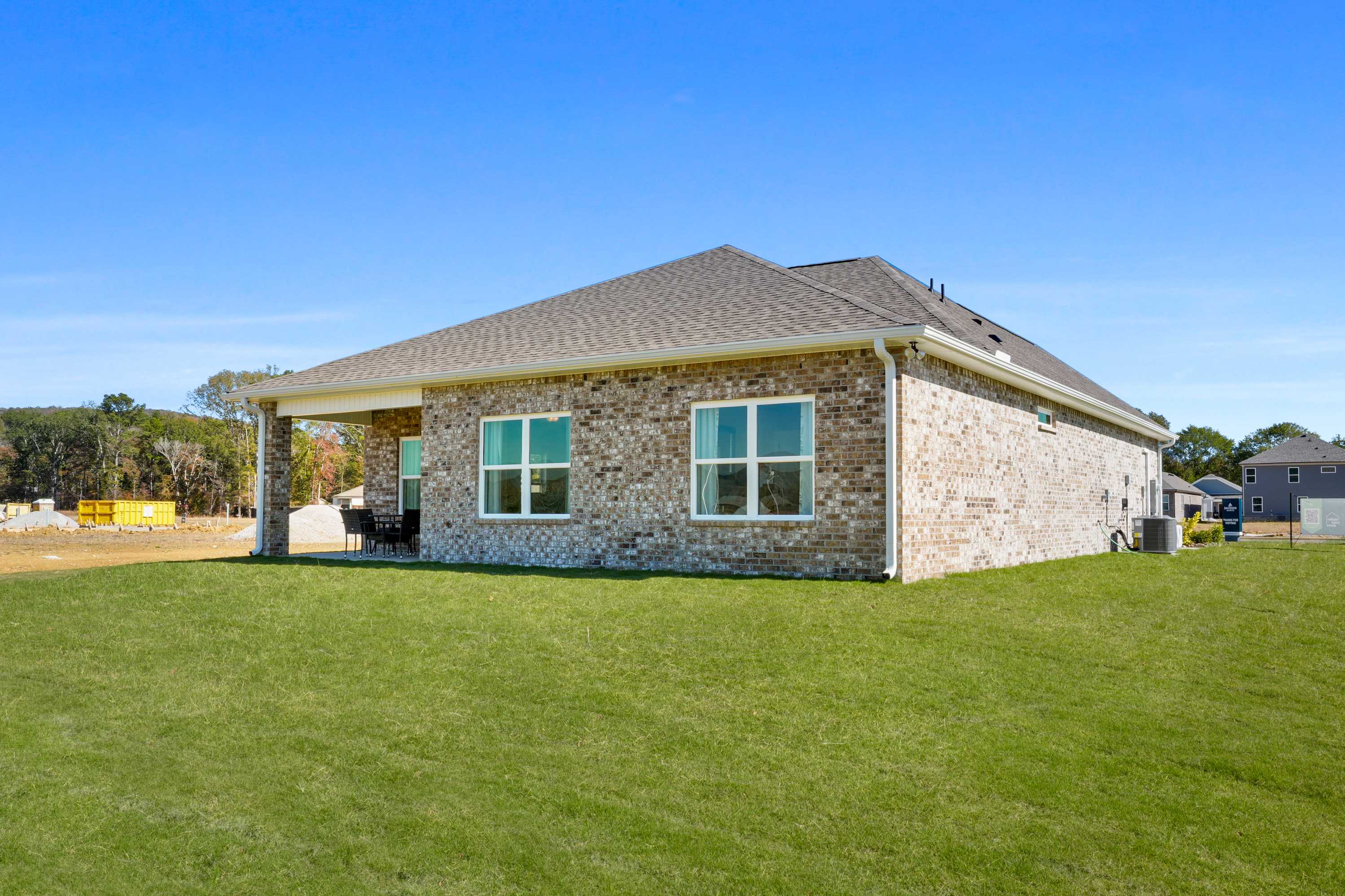 Brick home side exterior at Ramsay Cove in Owens Cross Roads, Alabama with covered patio, large windows, and green lawn