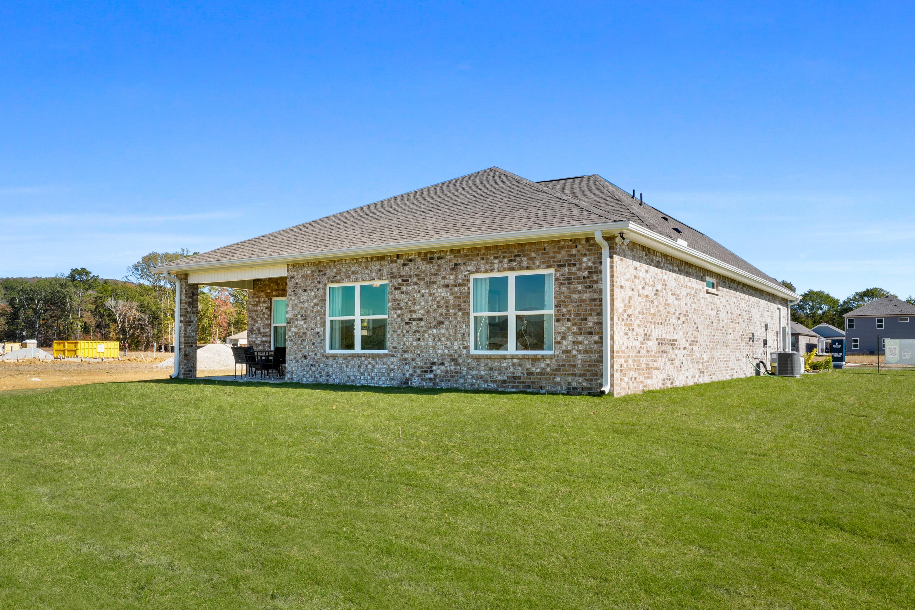 Brick home side exterior at Ramsay Cove in Owens Cross Roads, Alabama with covered patio, large windows, and green lawn
