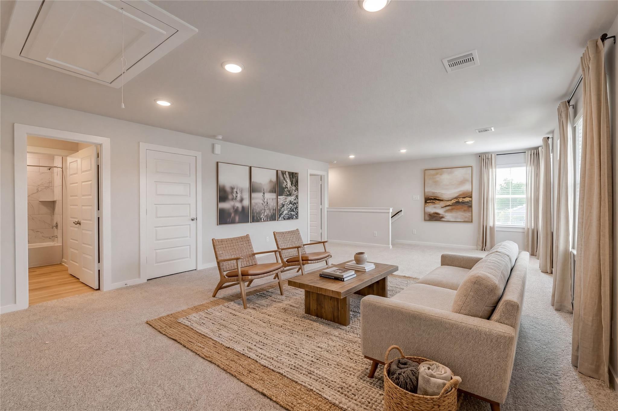 Cozy upstairs loft with beige sofa, rattan chairs, jute rug, and abstract art in Davidson Homes San Marcos E, Conroe, Texas