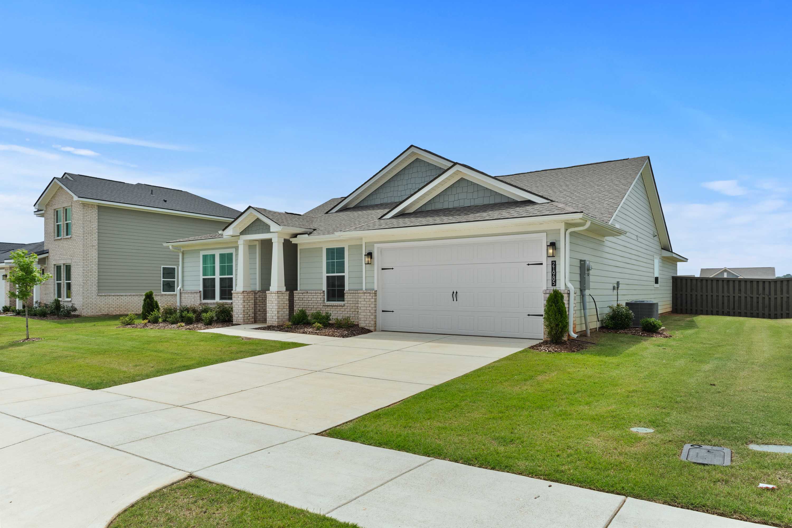 Contemporary gray craftsman-style home at Anderson Farm in Athens, Alabama with attached garage and lush front yard