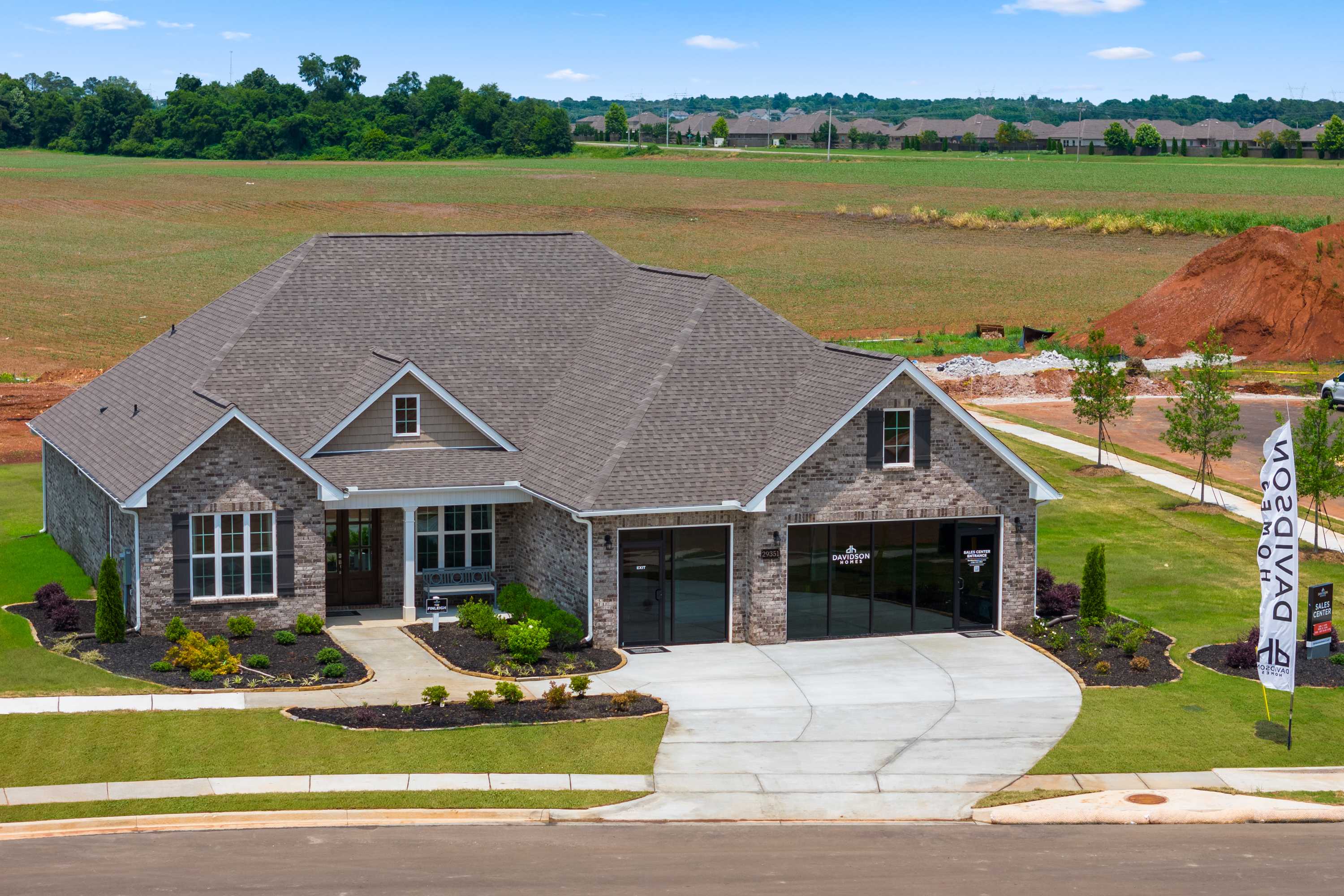Modern ranch-style home exterior in Creekside, Harvest Alabama by Davidson Homes with stone facade, garage, and lush landscaping