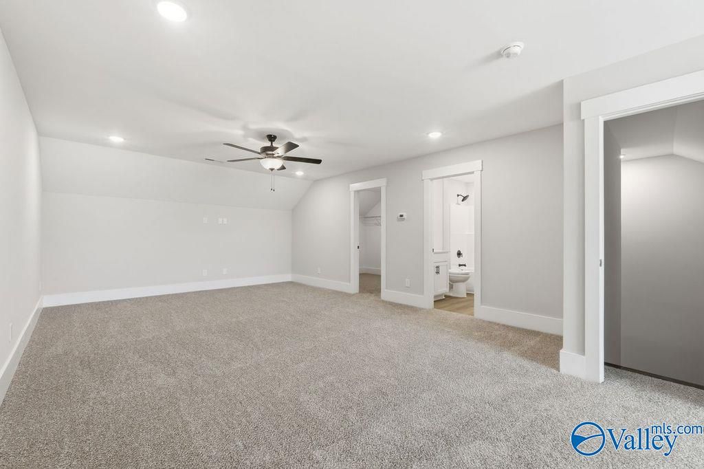 Spacious carpeted bonus room with ceiling fan, recessed lights, and adjacent bathroom in Davidson Homes The Rockford, Hartselle, Alabama