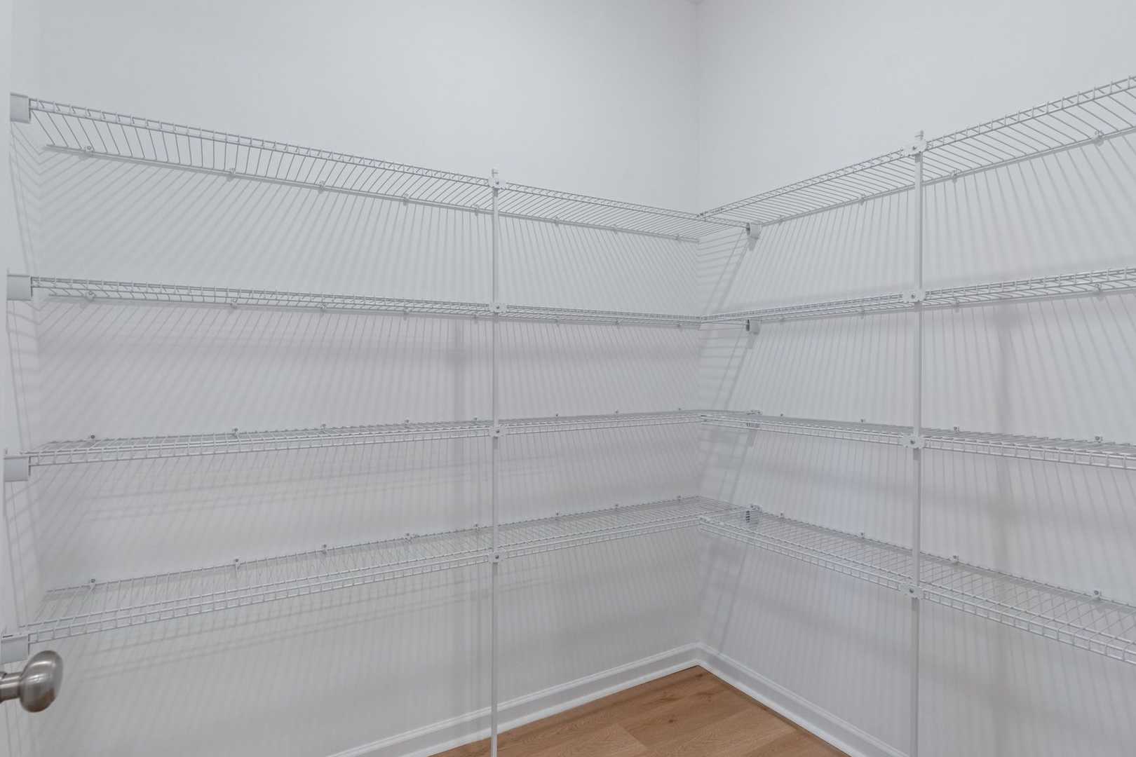 Spacious walk-in closet in The Luna master suite with white wire shelving, corner design, and hardwood floors