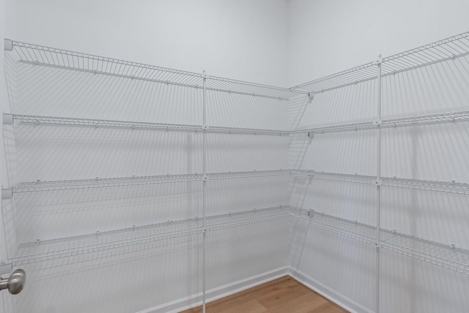 Spacious walk-in closet in The Luna master suite with white wire shelving, corner design, and hardwood floors