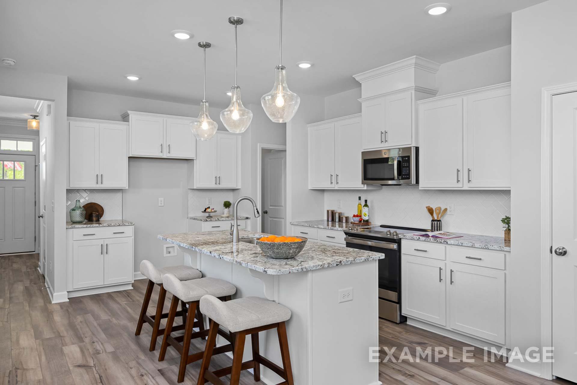 Spacious modern kitchen in The Carter B with white shaker cabinets, granite island, pendant lights, and stainless appliances