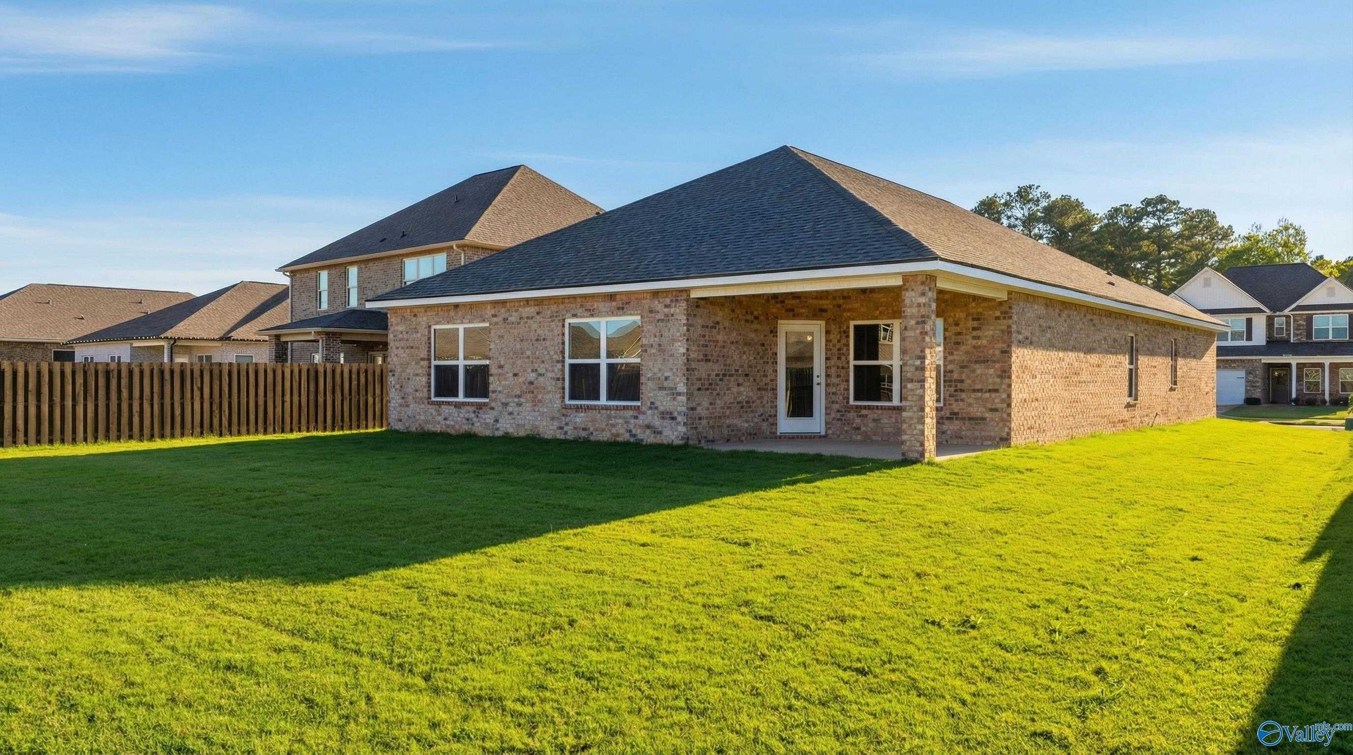 Single-story brick Everett home with gabled roof, large windows, lush green lawn and privacy fence in Creekside, Harvest, Alabama