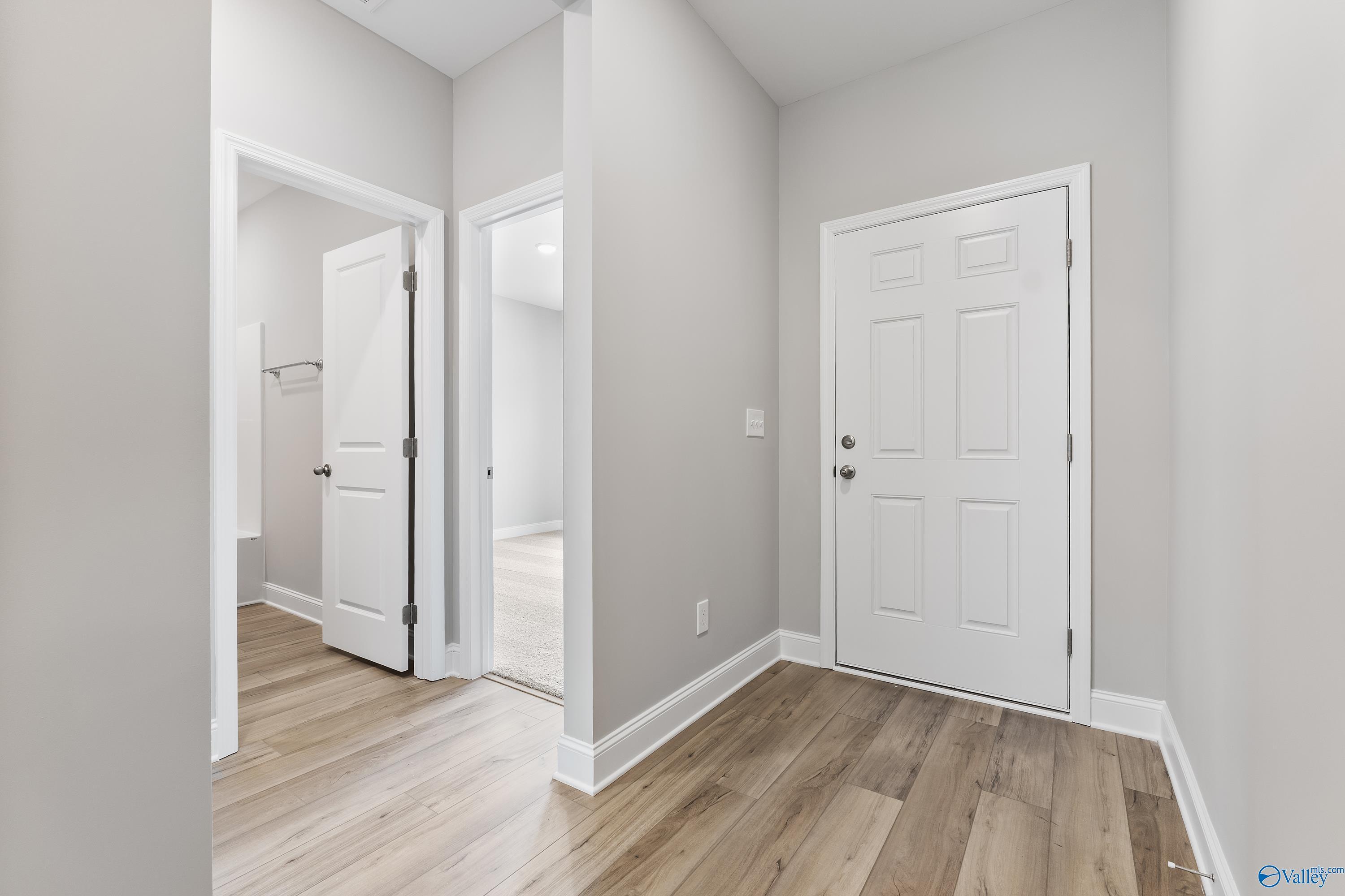 Bright hallway with hardwood floors, white doors, and open bedroom access in Davidson Homes The Franklin, Huntsville AL