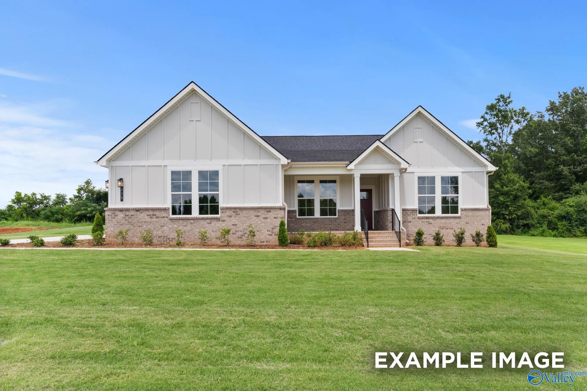 Modern white single-story home with brick accents, large windows, and covered porch in The Meadows at Hampton Cove, Owens Cross Roads, Alabama