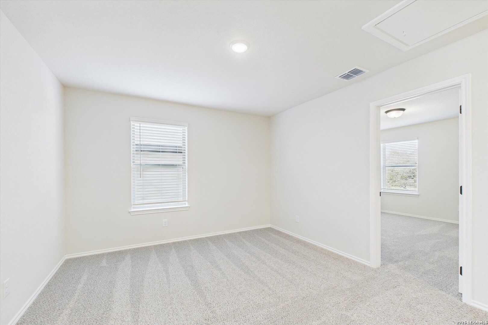 Bright secondary bedroom with neutral walls, beige carpet, and window blinds in Davidson Homes The Gillian B, San Antonio