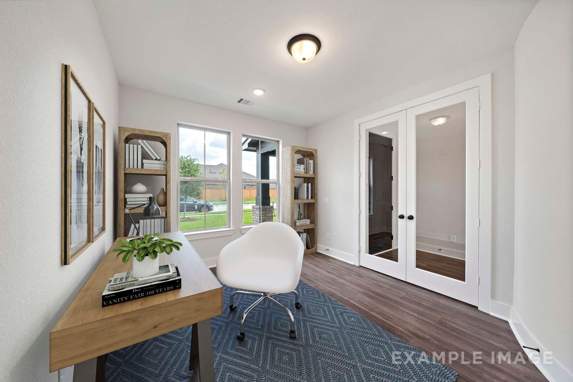 Bright home office in The Victoria by Davidson Homes featuring French doors, wood desk, white chair, and natural light.