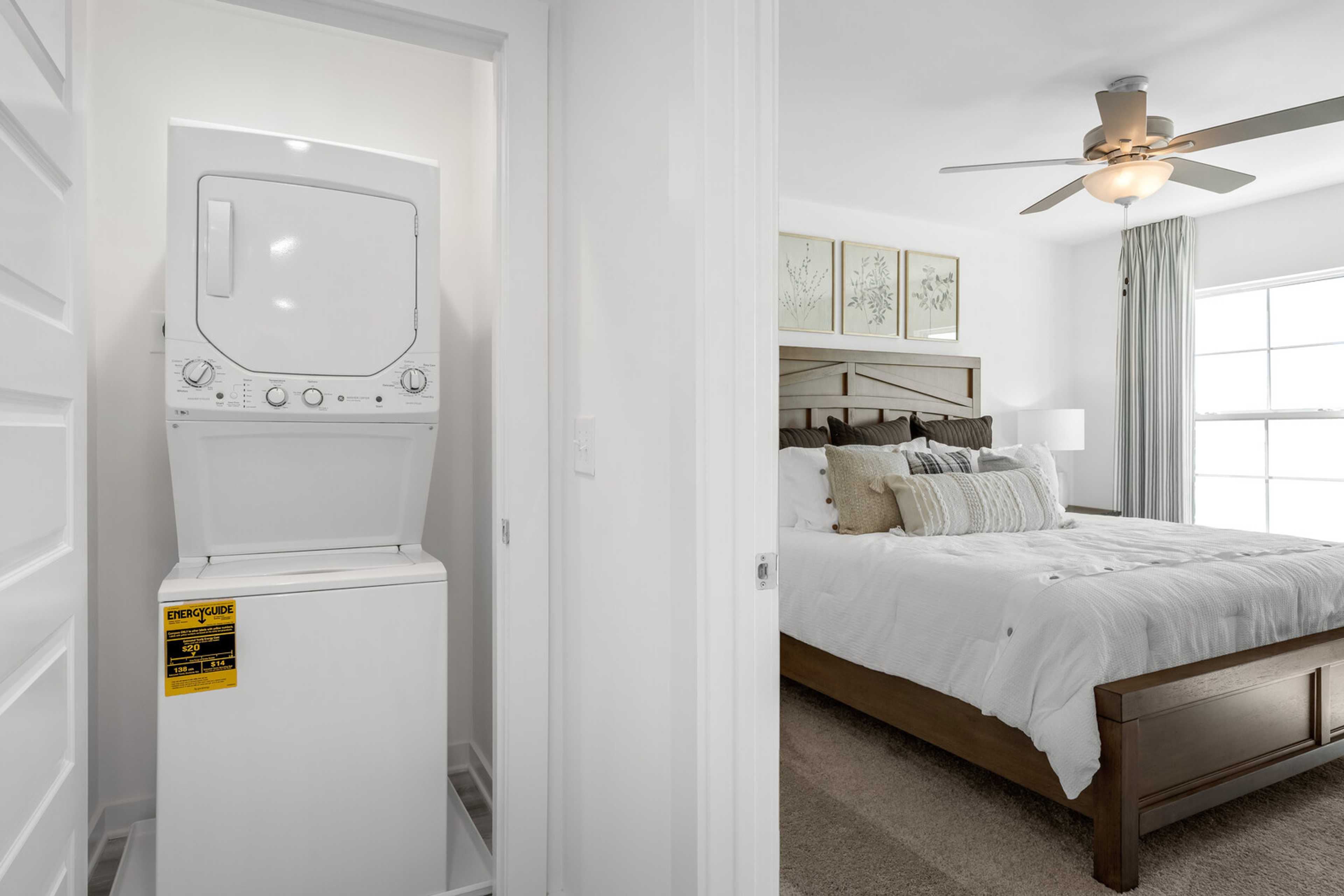 Stacked washer dryer in laundry room adjacent to cozy bedroom at The Towns at Red River, Gallatin TN by Davidson Homes