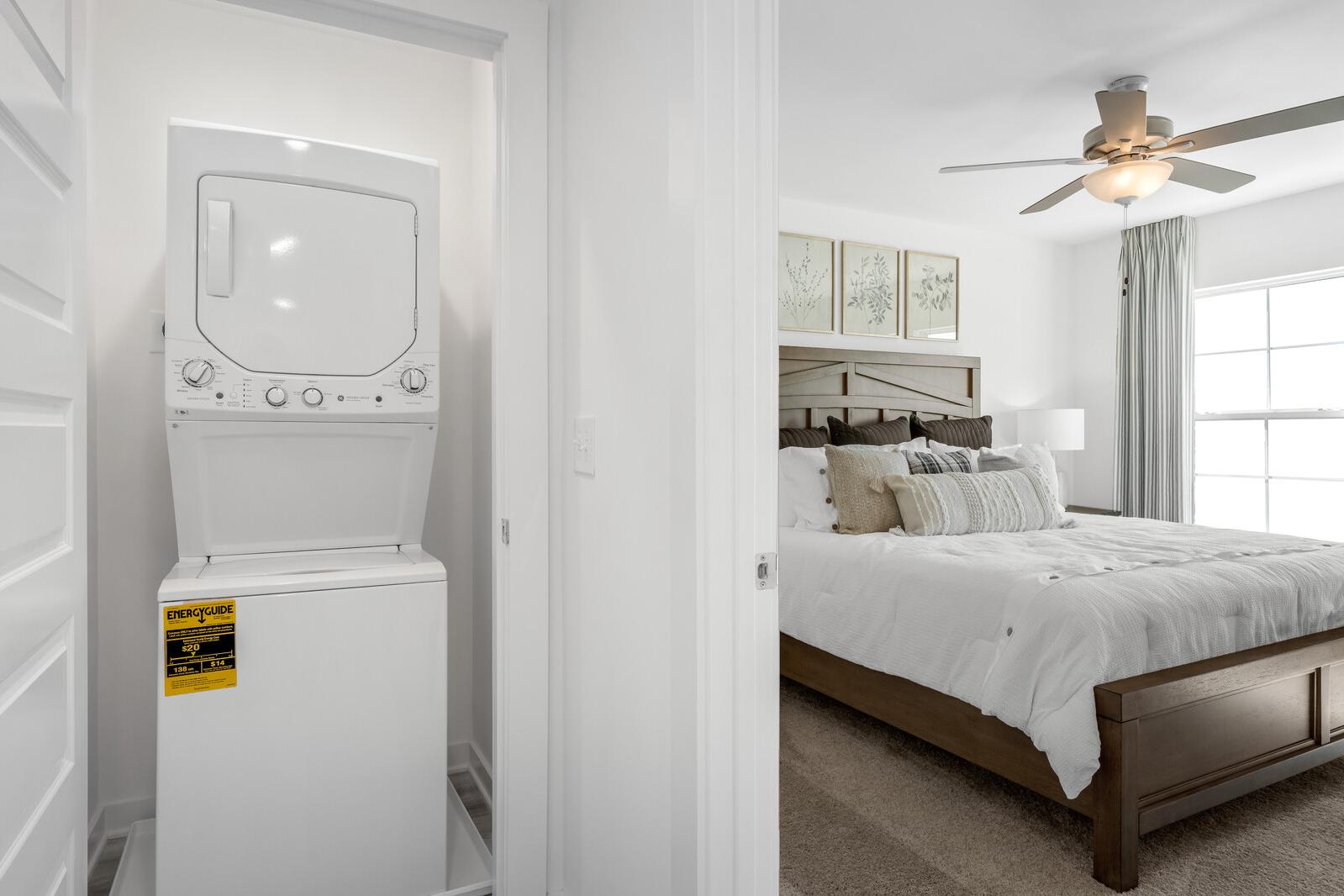 Stacked washer dryer in laundry room adjacent to cozy bedroom at The Towns at Red River, Gallatin TN by Davidson Homes