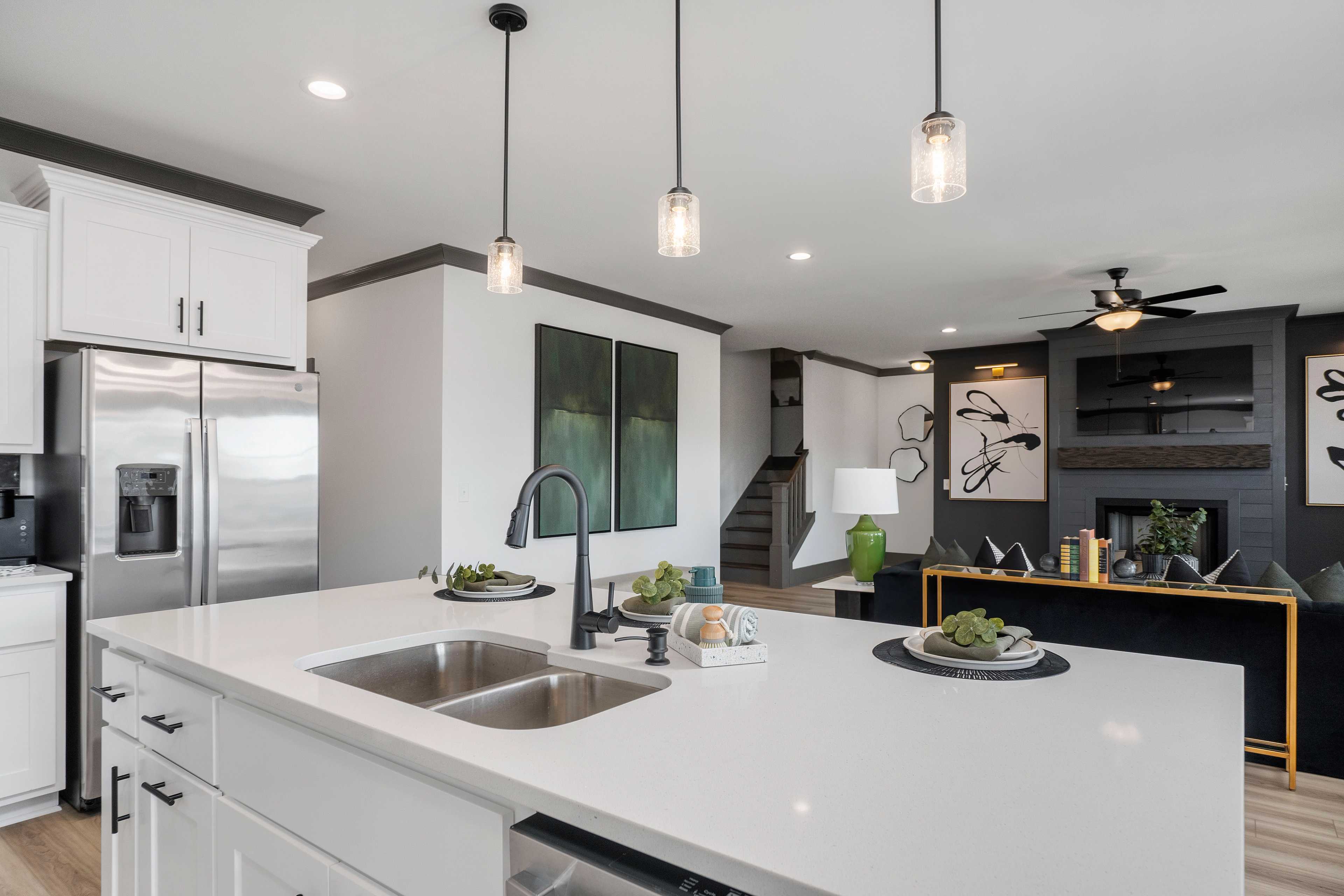 Spacious modern kitchen in Barnett's Crossing, Madison AL with white cabinets, quartz island, stainless appliances, and abstract art