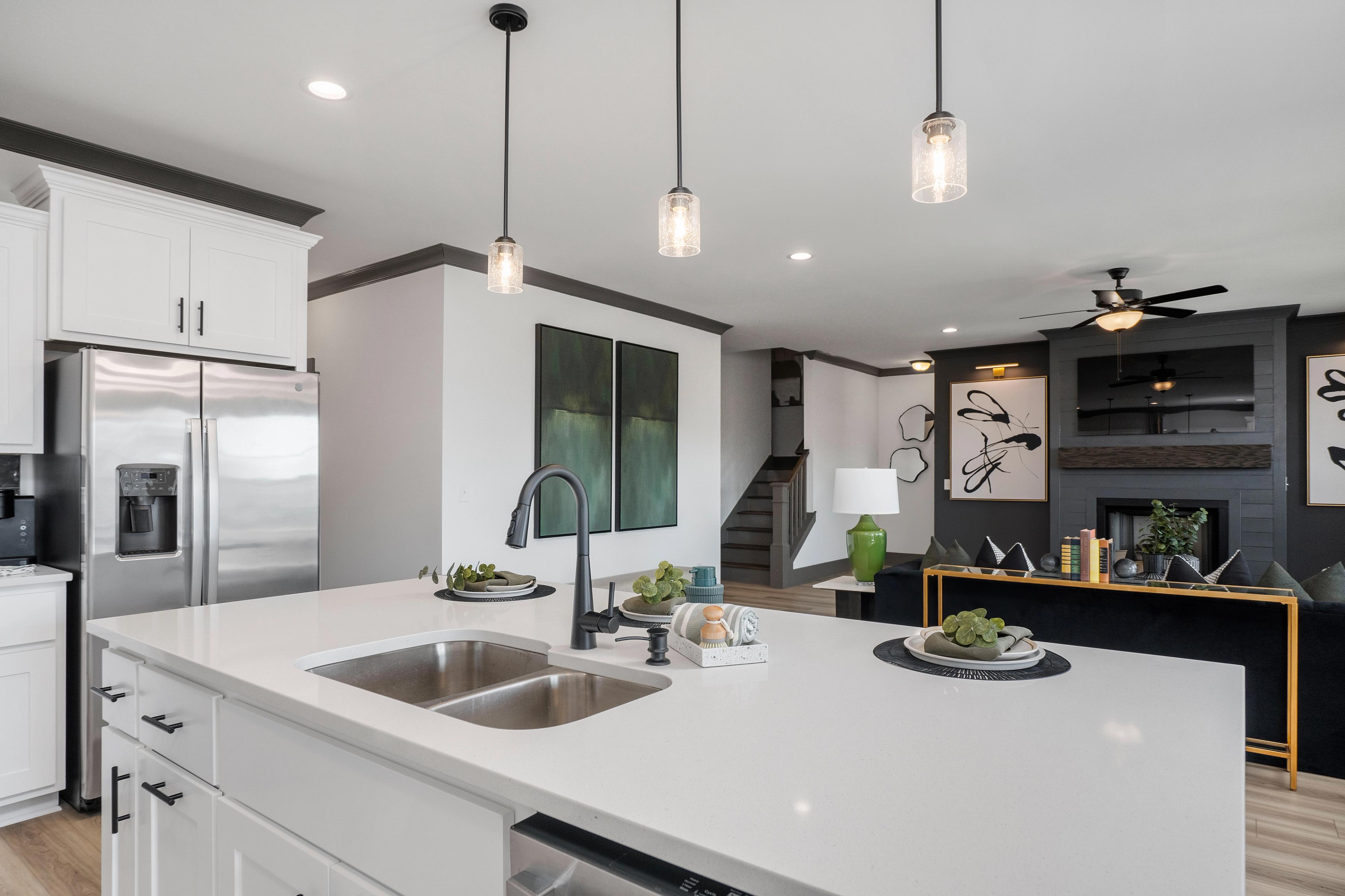 Spacious modern kitchen in Barnett's Crossing, Madison AL with white cabinets, quartz island, stainless appliances, and abstract art