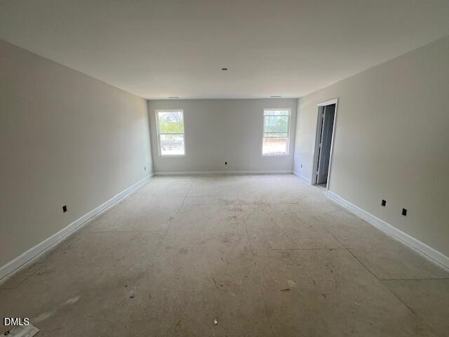 Empty upstairs bonus room with large windows, neutral walls, and hardwood subfloor in 4-bedroom Preston A home, Lillington, NC