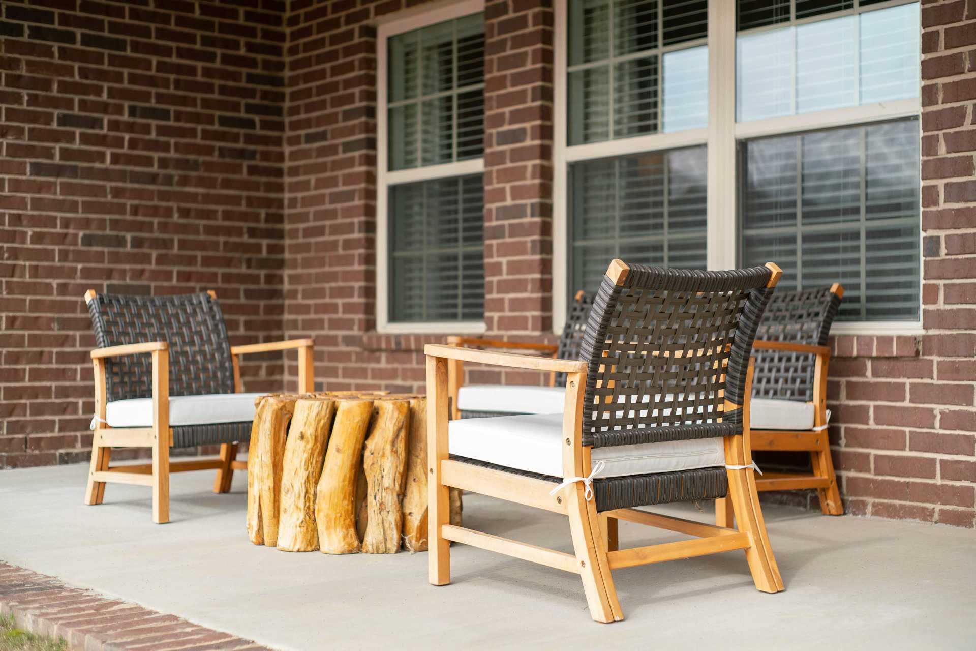 Cozy wicker patio seating at The Dairy at Oak Grove in South Huntsville AL with tree stump table and brick wall backdrop