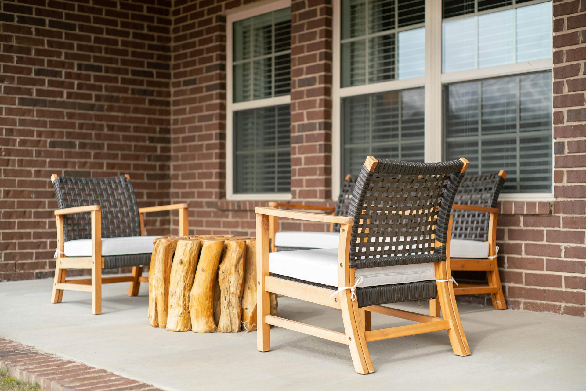 Cozy wicker patio seating at The Dairy at Oak Grove in South Huntsville AL with tree stump table and brick wall backdrop