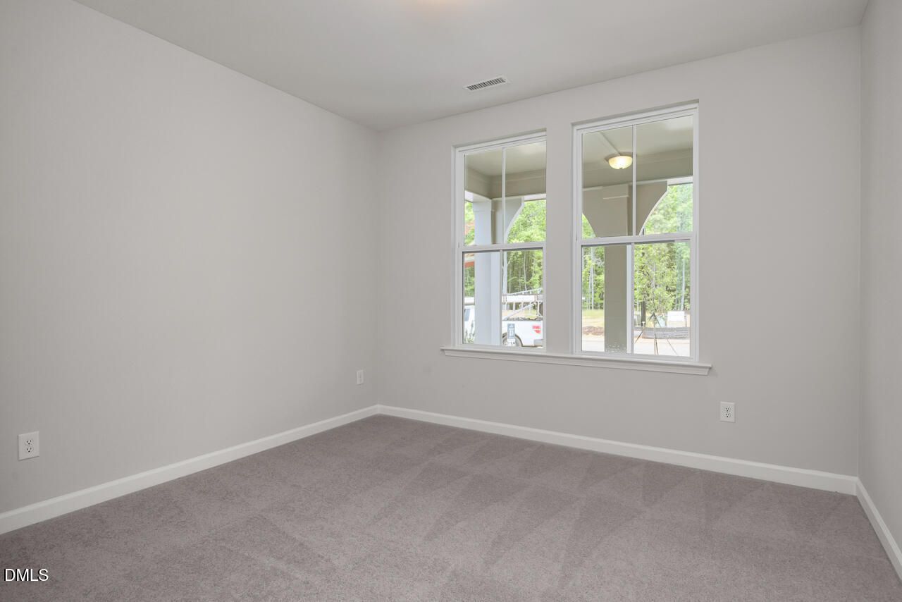 Bright, carpeted bedroom with large windows in The Ashport G floor plan at Sage on North Main in Wake Forest, NC.