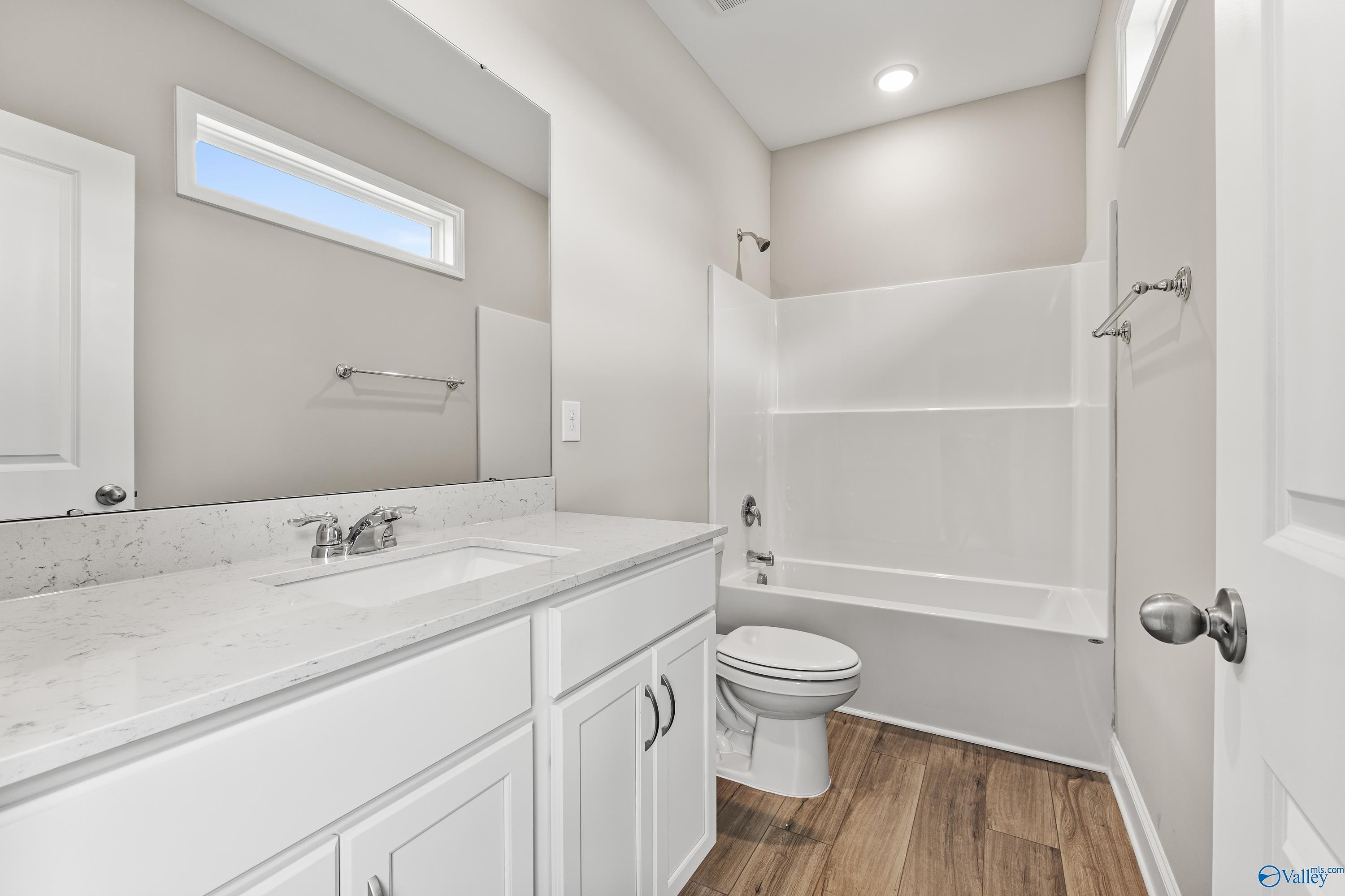 Contemporary bathroom with quartz vanity, tub-shower combo, and luxury vinyl plank flooring in Davidson Homes The Daphne C, Harvest AL