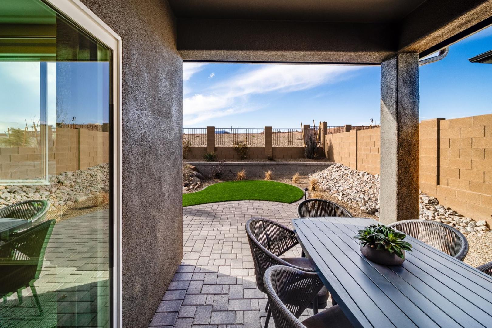 Spacious covered patio of The Newport C with outdoor dining table, wicker chairs, potted plant, and landscaped courtyard in Prescott Arizona