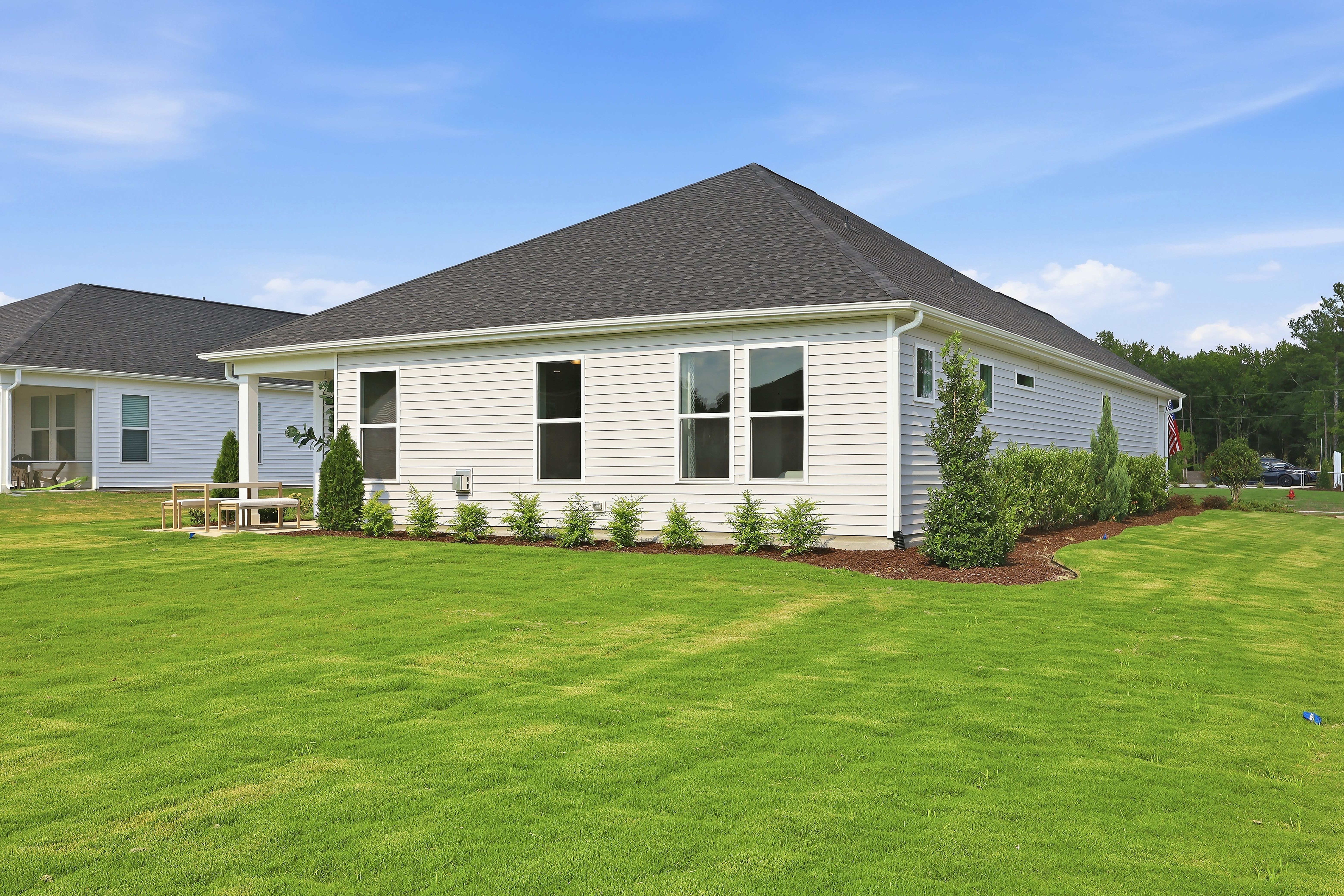 Back exterior view of The Daphne D home design by Davidson Homes in Lillington, NC, featuring a large yard and patio.