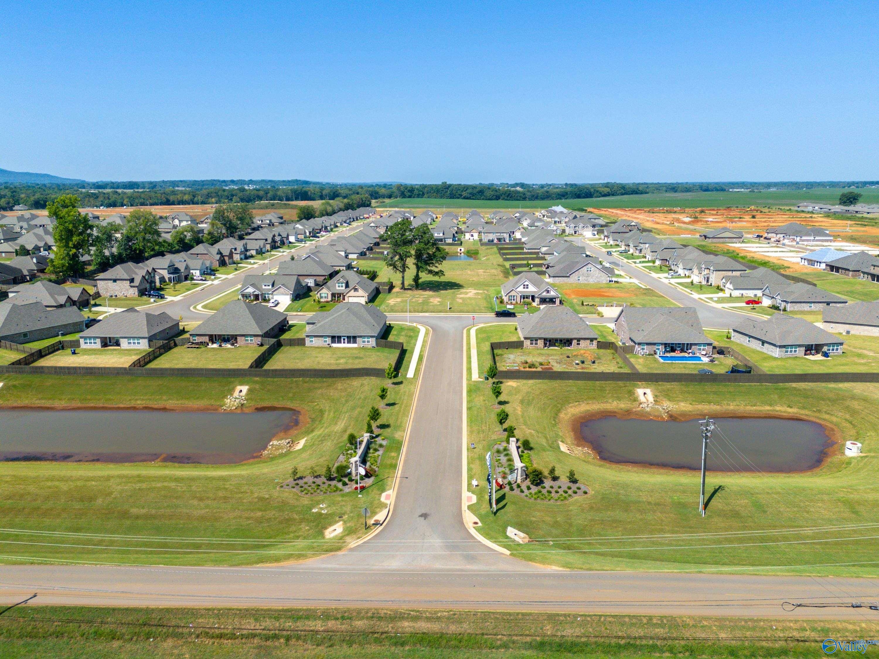 Aerial view of modern single-story homes in Pikes Ridge, Meridianville, Alabama, with ponds, green lawns and Davidson Homes Lanier plan