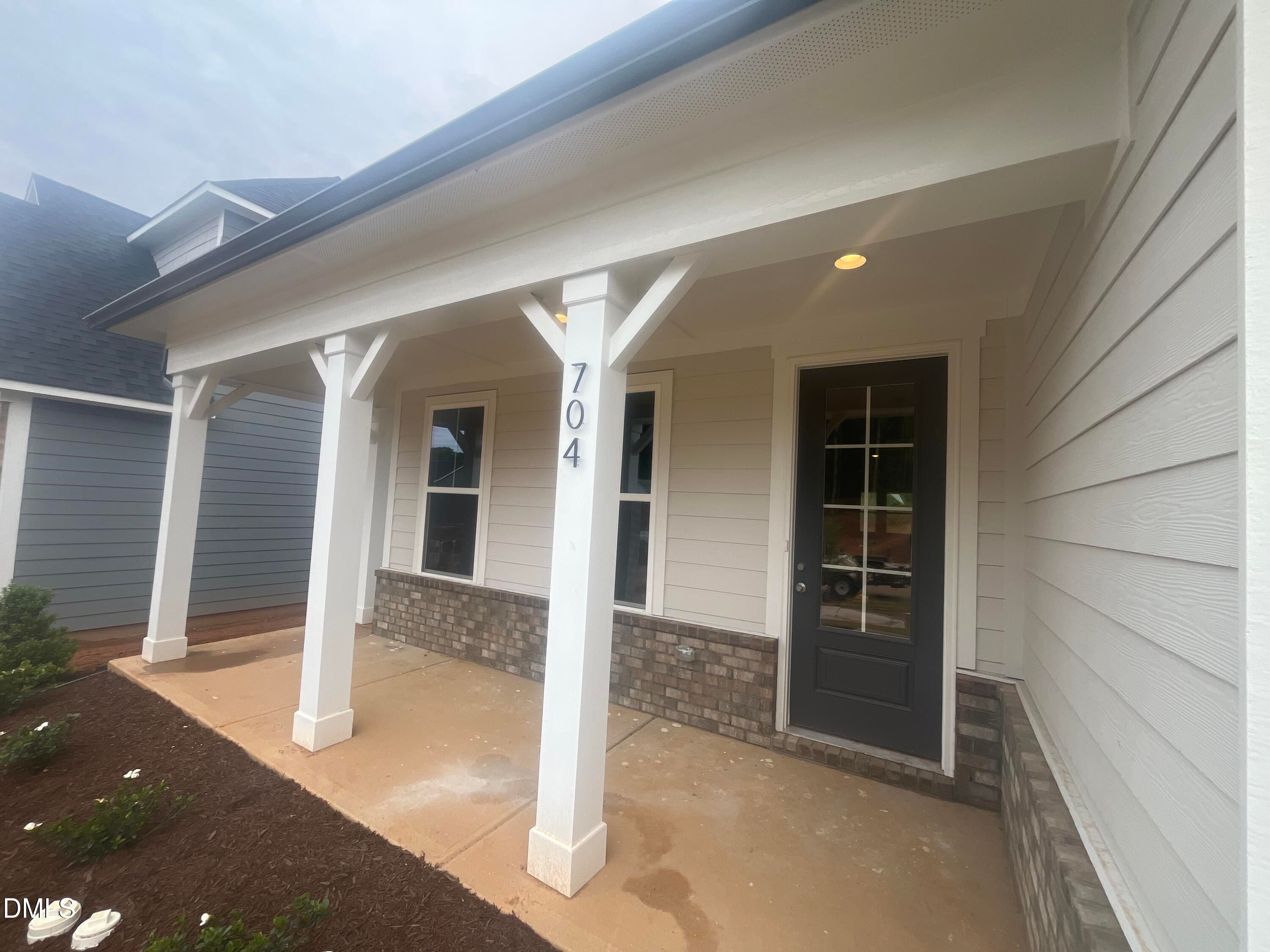Charming front porch with white columns, dark glass entry door, and house number 704 in Davidson Homes The Birch II E, Wake Forest, NC