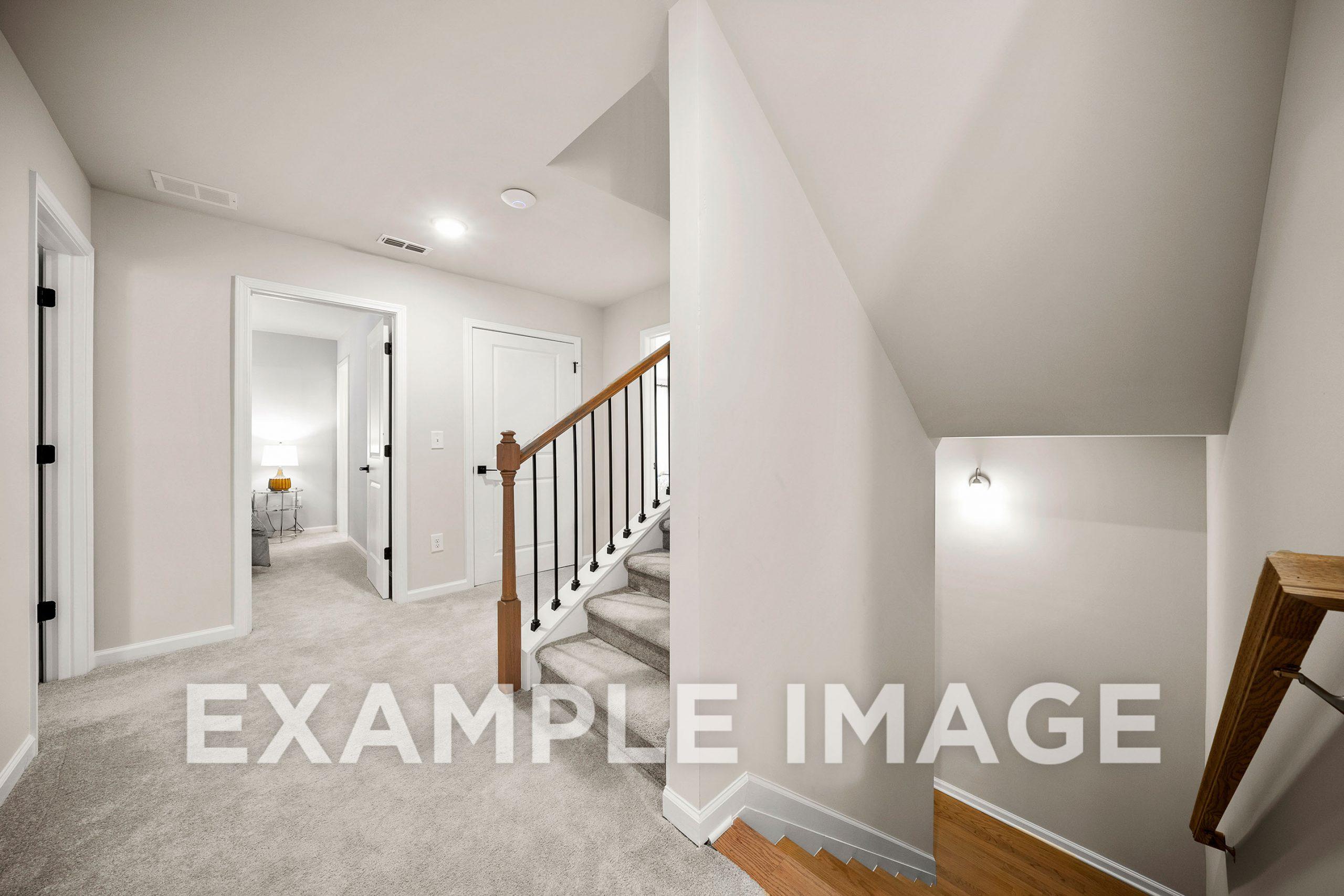 Upper floor hallway of The Hickory B showcasing wooden staircase, beige carpet, and bedroom doors in Davidson Homes design