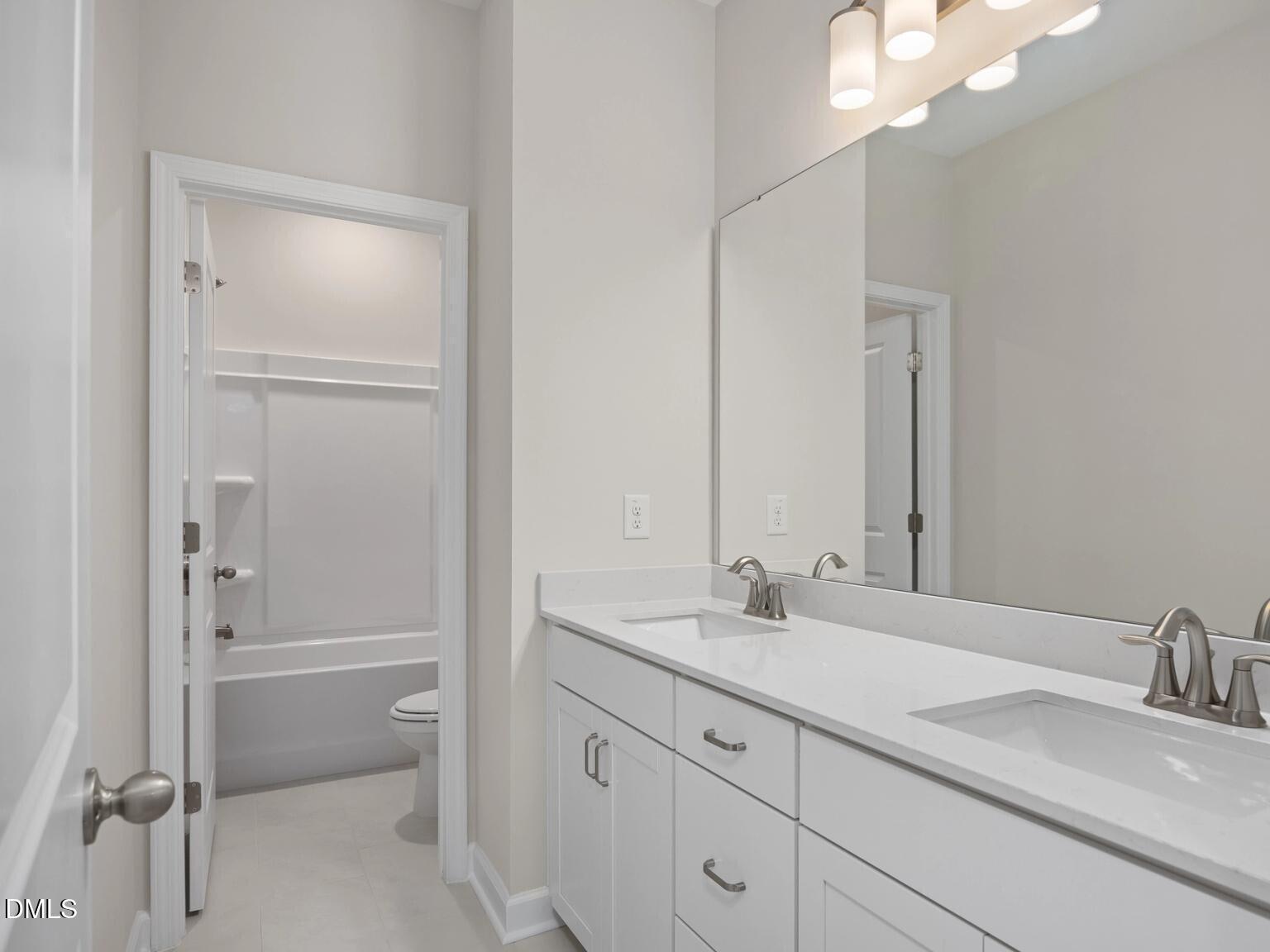 Modern double-sink vanity with white cabinets, bathtub, and shower in Davidson Homes The Beech B, Wake Forest, NC