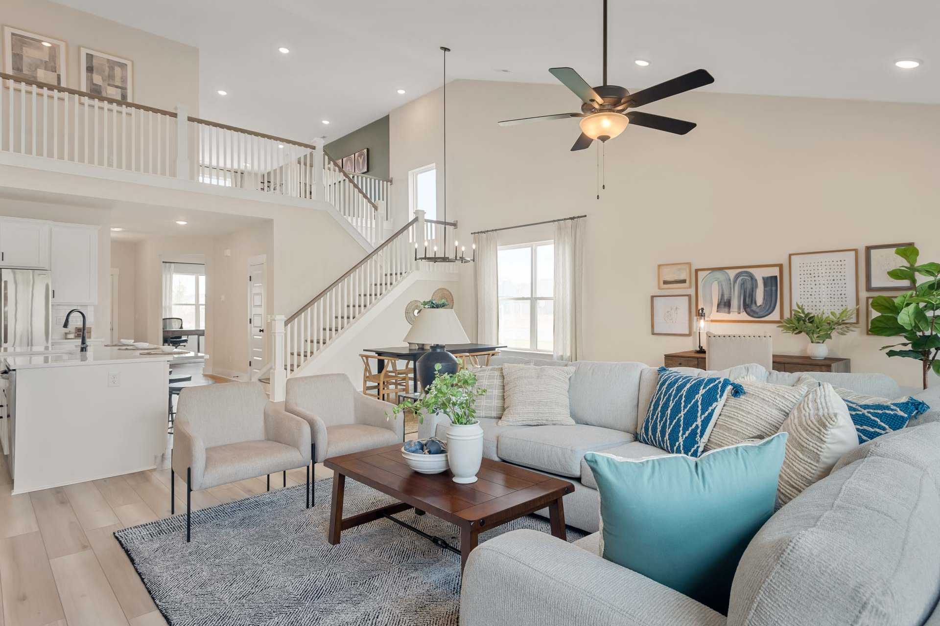 Open-concept living room and kitchen at Salem Landing in Murfreesboro TN with hardwood floors, beige walls, ceiling fans, and modern sofa