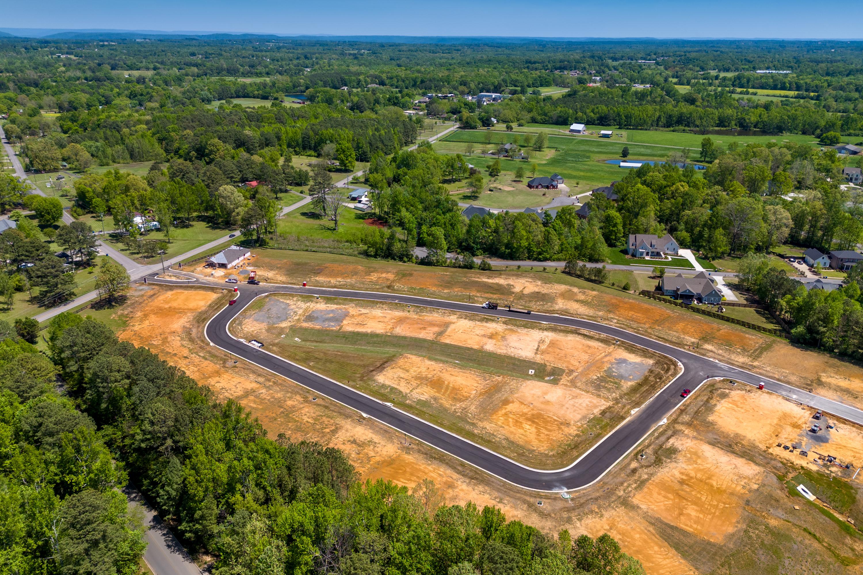 Aerial view of developing home lots and curved roads at The Highlands in Arab Alabama surrounded by dense green forests