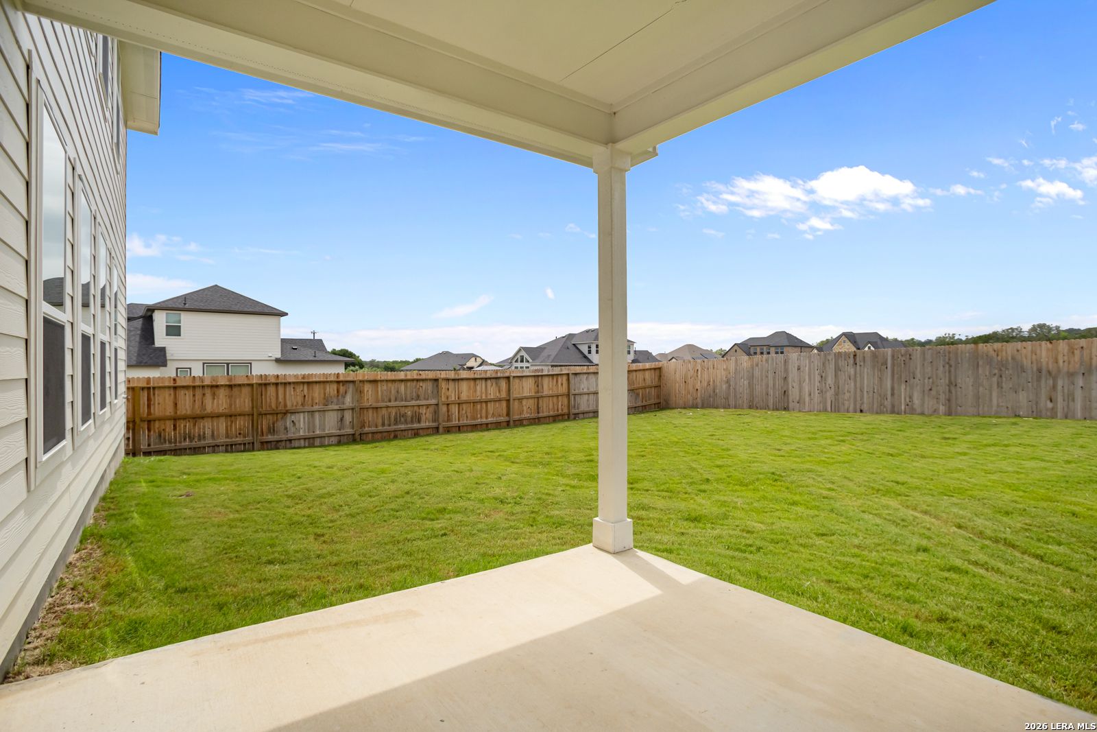 Covered back patio with a spacious fenced backyard at The Danbury H model in The Reserve at Potranco Oaks, Castroville, TX.