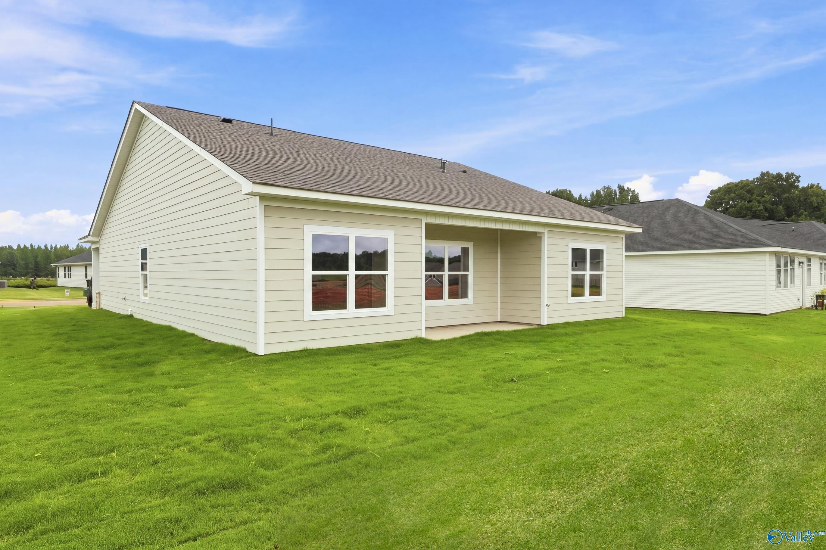 Rear exterior view of 1-story Asheville E home with covered patio and green lawn in Forest Glen, Hazel Green, Alabama.