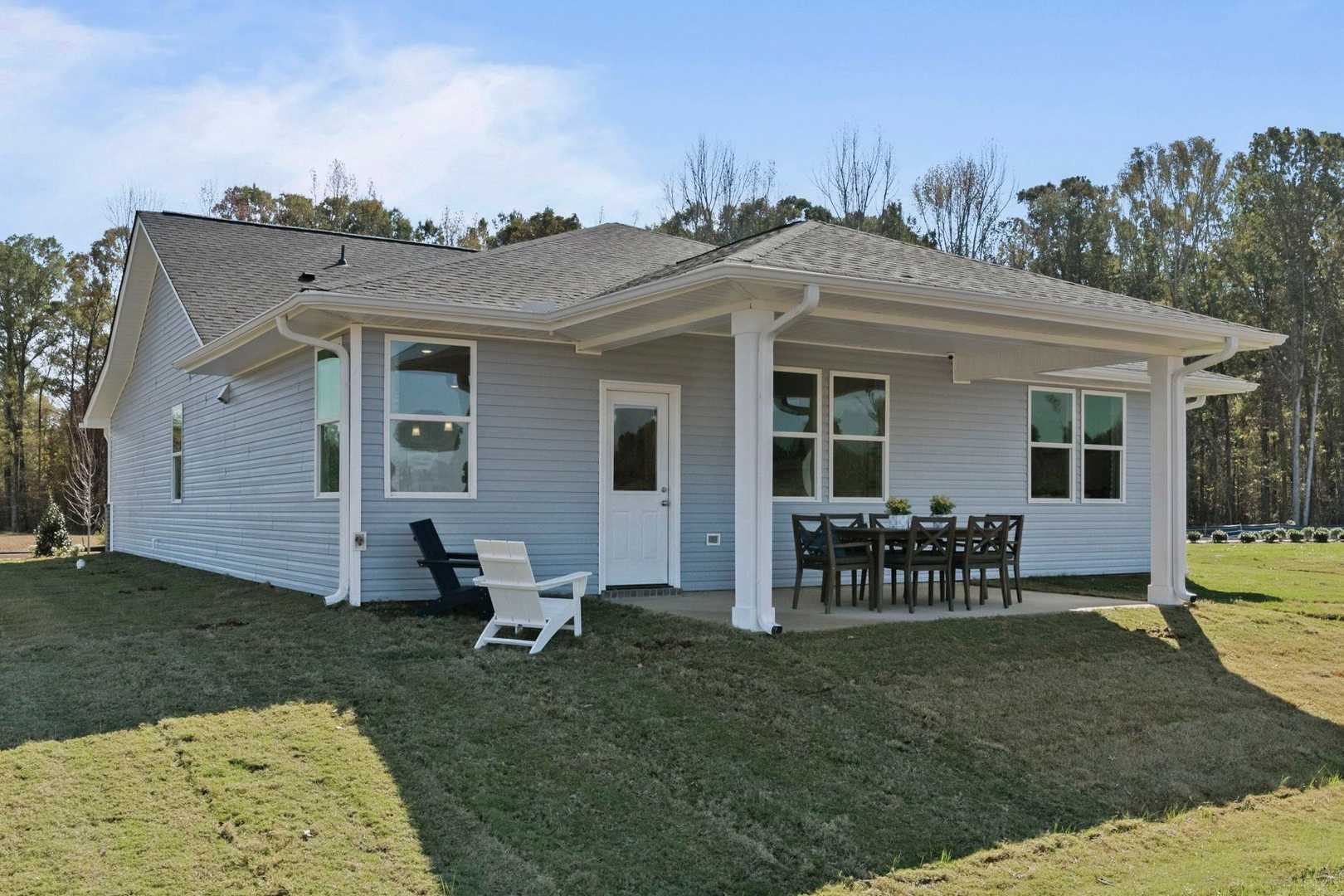 Rear view of The Phoenix 3-bedroom single-story home with covered porch, windows, and outdoor dining setup in Perry, Georgia
