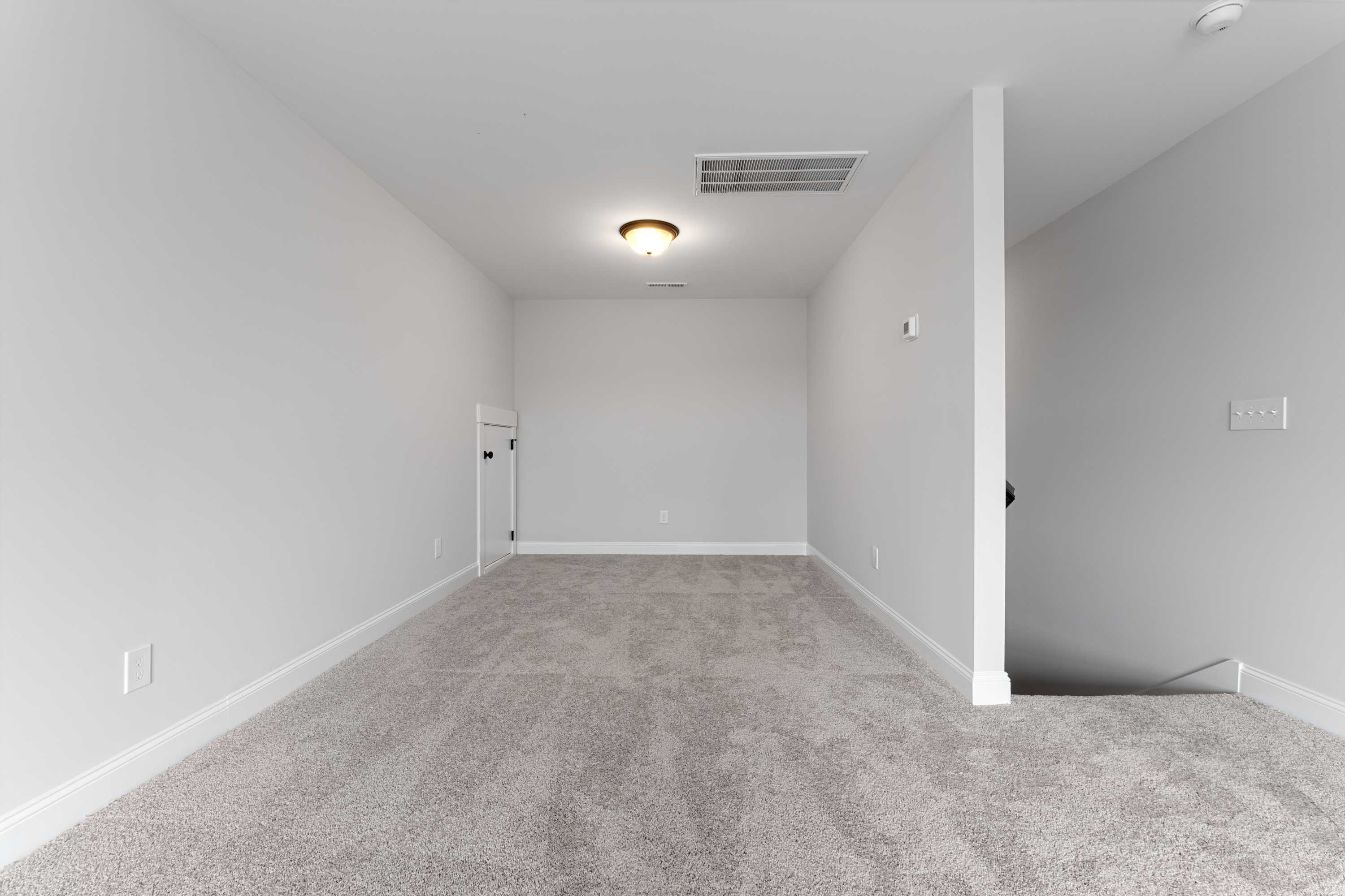 Spacious empty upstairs bonus room in The Copeland 2-story home by Davidson Homes, gray carpet, neutral walls, stairs access