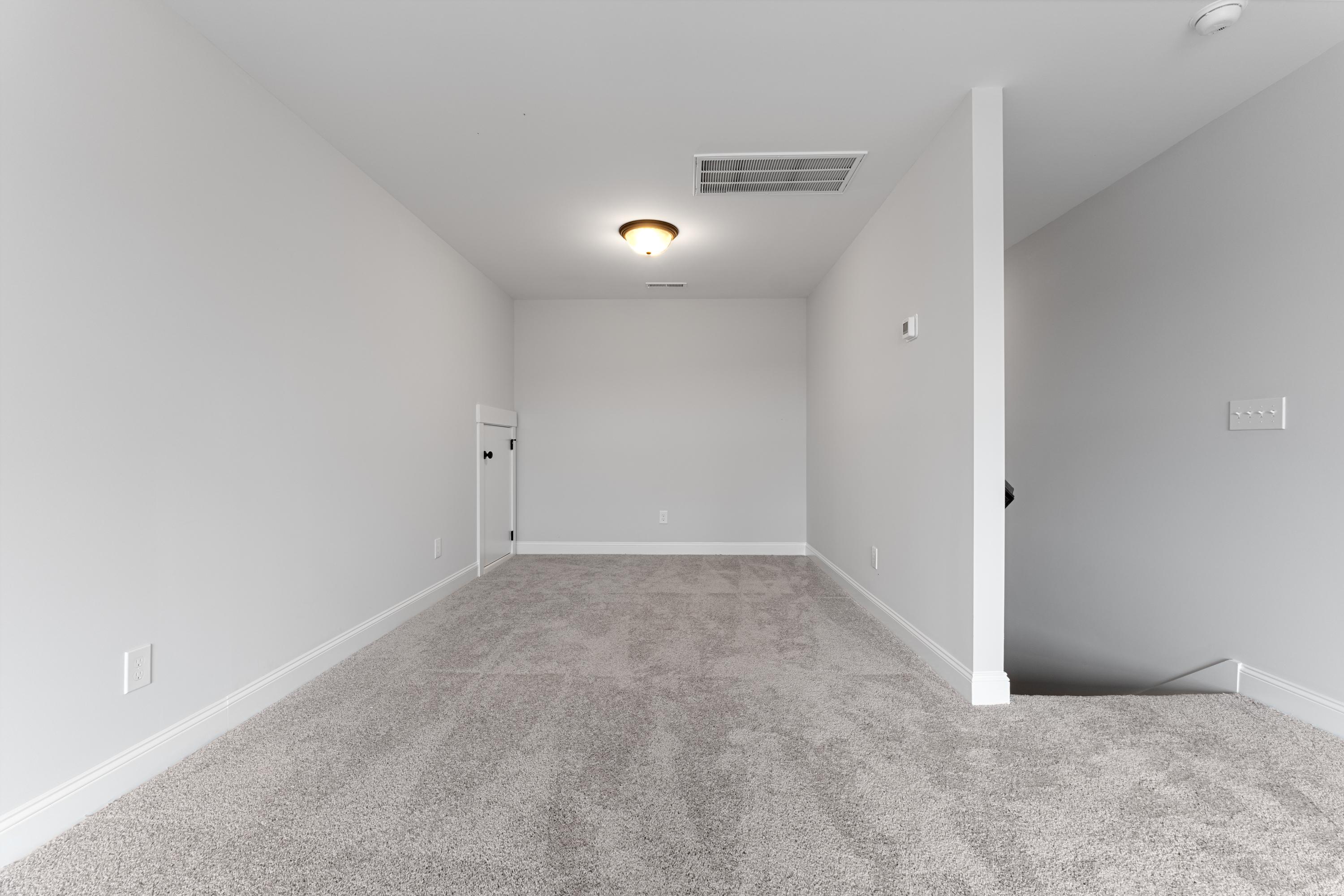 Spacious upstairs bonus room in The Copeland 2-story home with carpeted flooring, white walls, and stair access