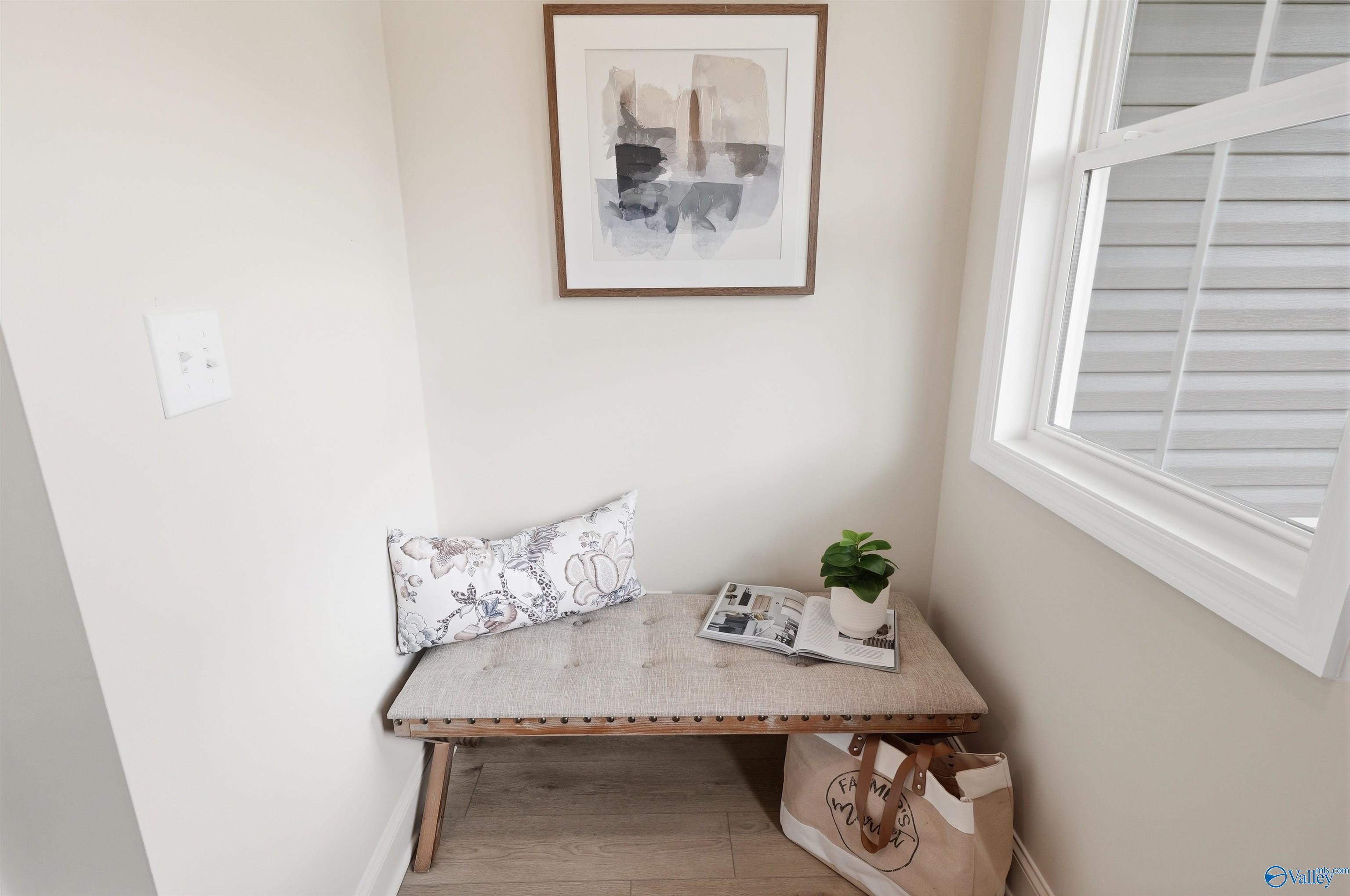 Cozy entry nook with upholstered bench, floral pillow, and framed art in Davidson Homes' The Russell A, Spragins Cove, Huntsville
