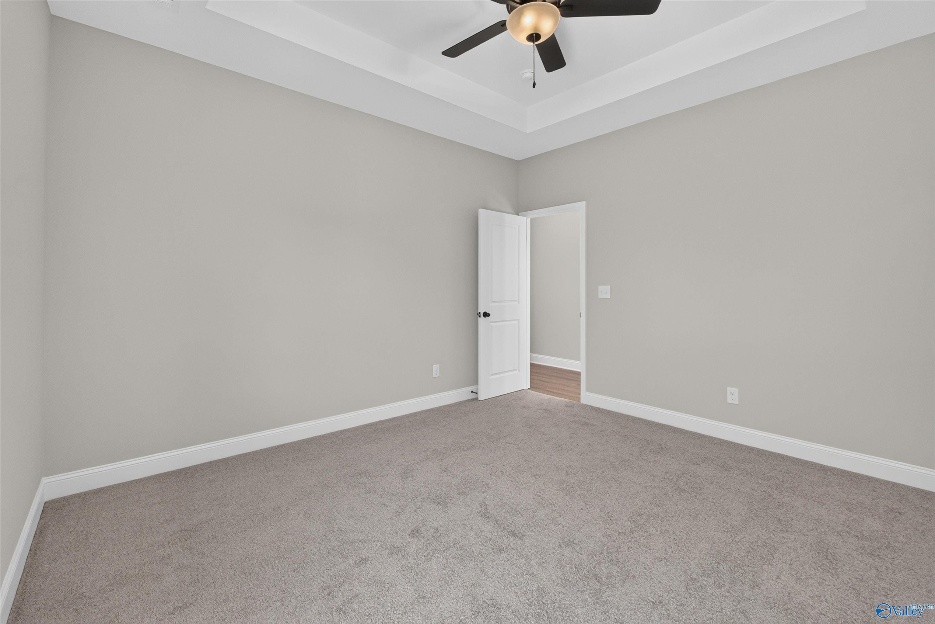 Spacious carpeted bedroom with tray ceiling and ceiling fan in Davidson Homes The Butler floor plan, Hazel Green, Alabama