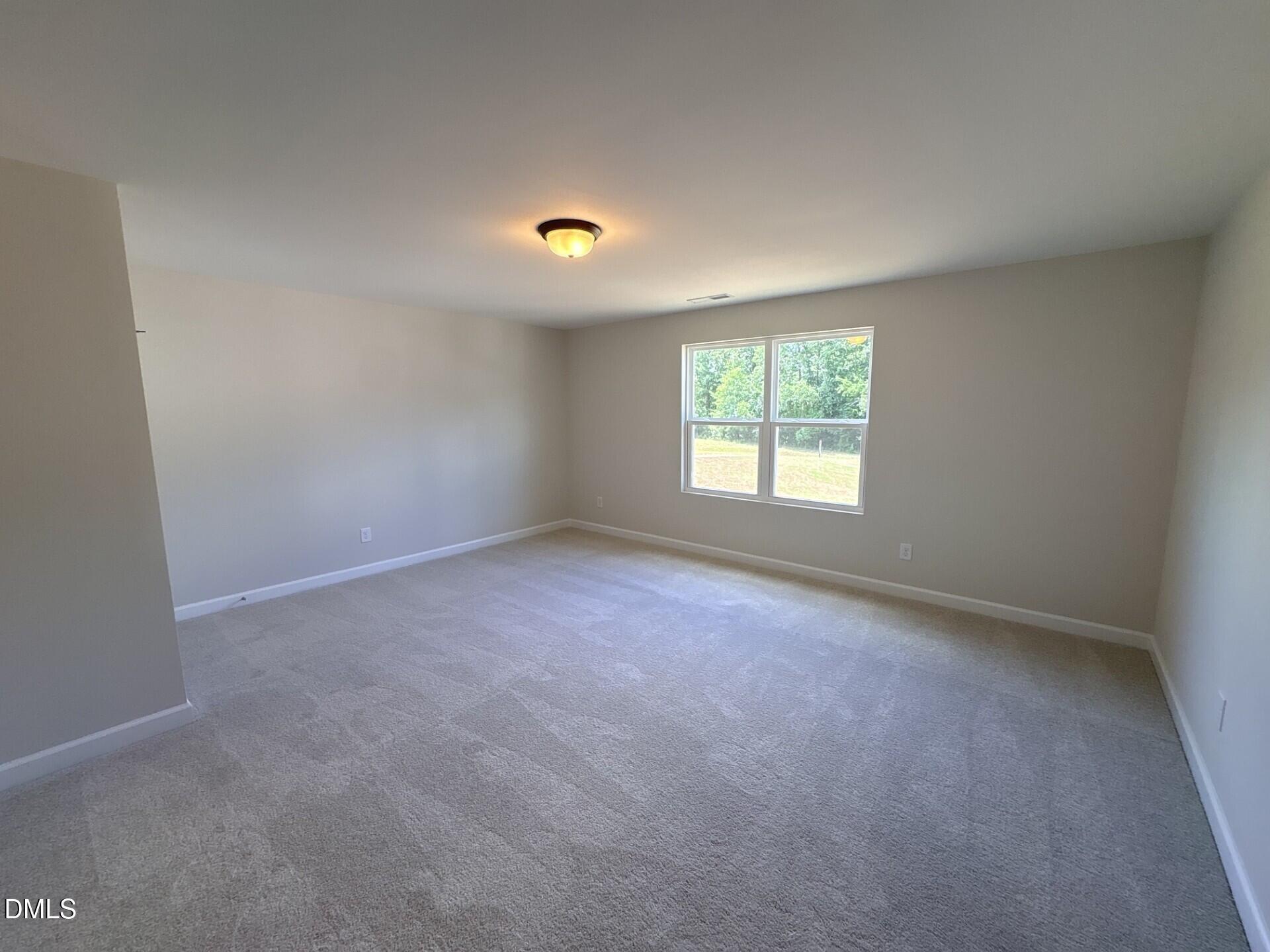 Spacious carpeted bedroom with neutral walls in The Ash C floor plan at Woodland Crossing in Zebulon, North Carolina.