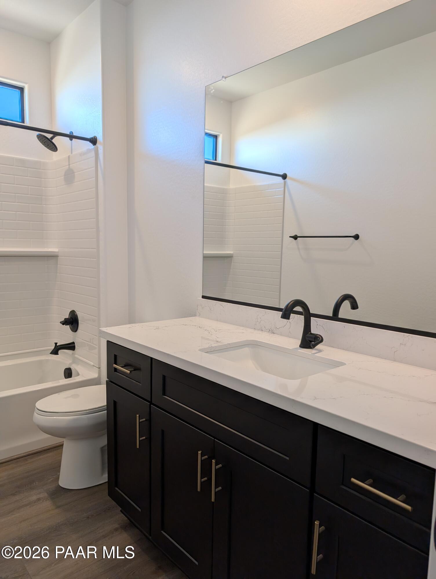 Modern guest bathroom with white tiled shower, soaking tub, dark cabinetry, quartz vanity, black fixtures in The Sheridan II G, Prescott AZ