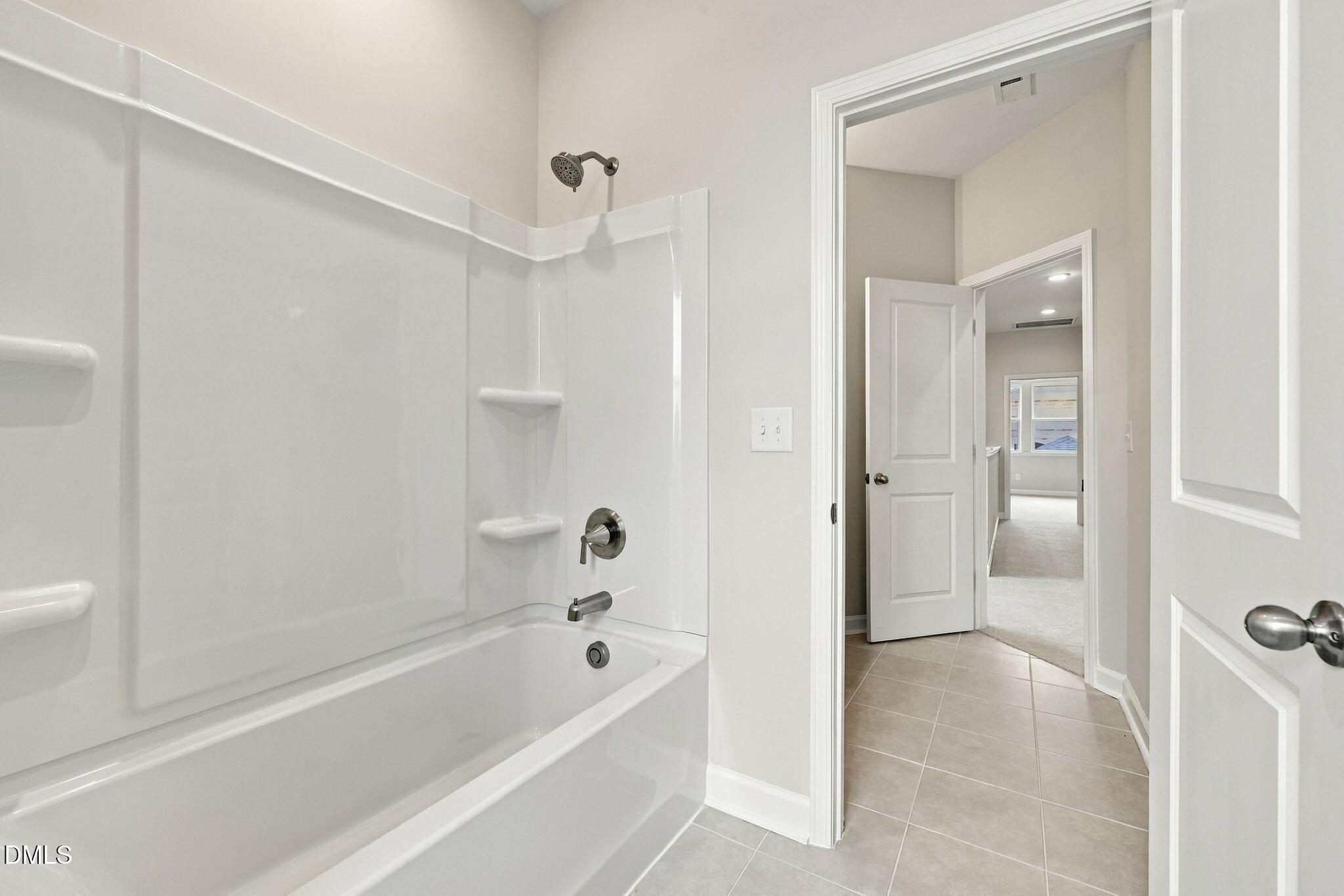 White tub-shower combo with brushed nickel fixtures and tile floor in bathroom of Davidson Homes' The Alexander B, Knightdale, NC