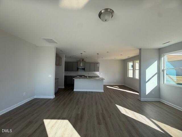 Open-concept kitchen with gray cabinets, large island, and hardwood floors in The Gavin B home, Lillington, NC