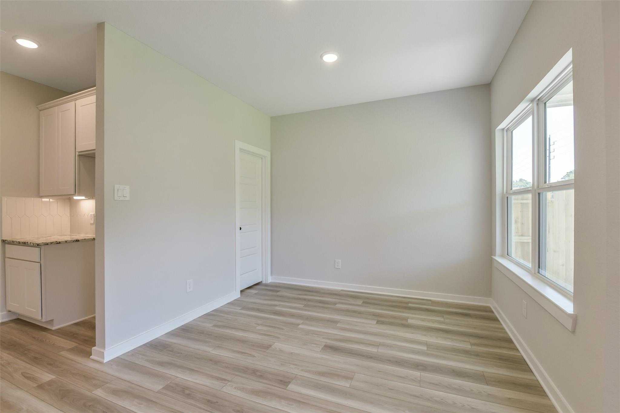Modern laundry room with white shaker cabinets, quartz sink countertop, and vinyl plank flooring in Davidson Homes The Daphne H, Crosby Texas
